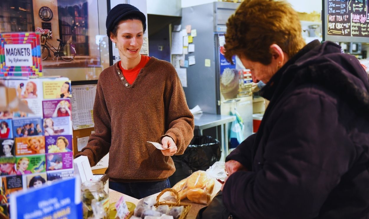 Gettyimages - 1315461761, Barbara Goodling, of Wyomissing purchases fasnachts from Dosie Dough employee Troy Turner, 24, of Sinking Spring inside the bakery.