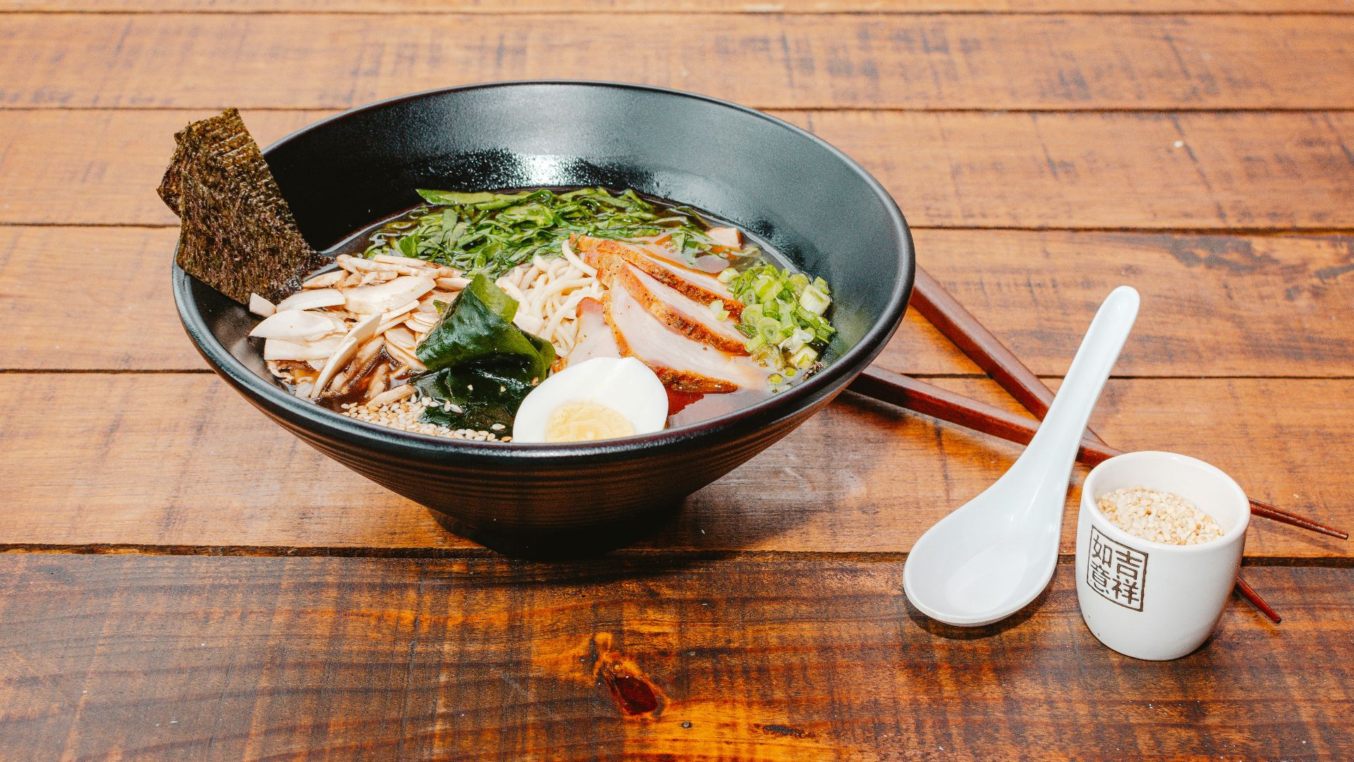 A bowl of food with chopsticks on a wooden table
