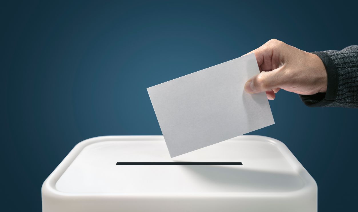 Man putting a ballot paper into a voting box concept for election, freedom and democracy - stock photo