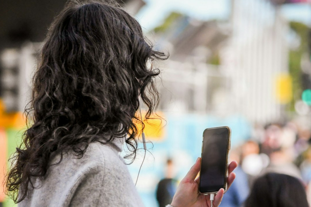 woman in gray sweater holding smartphone