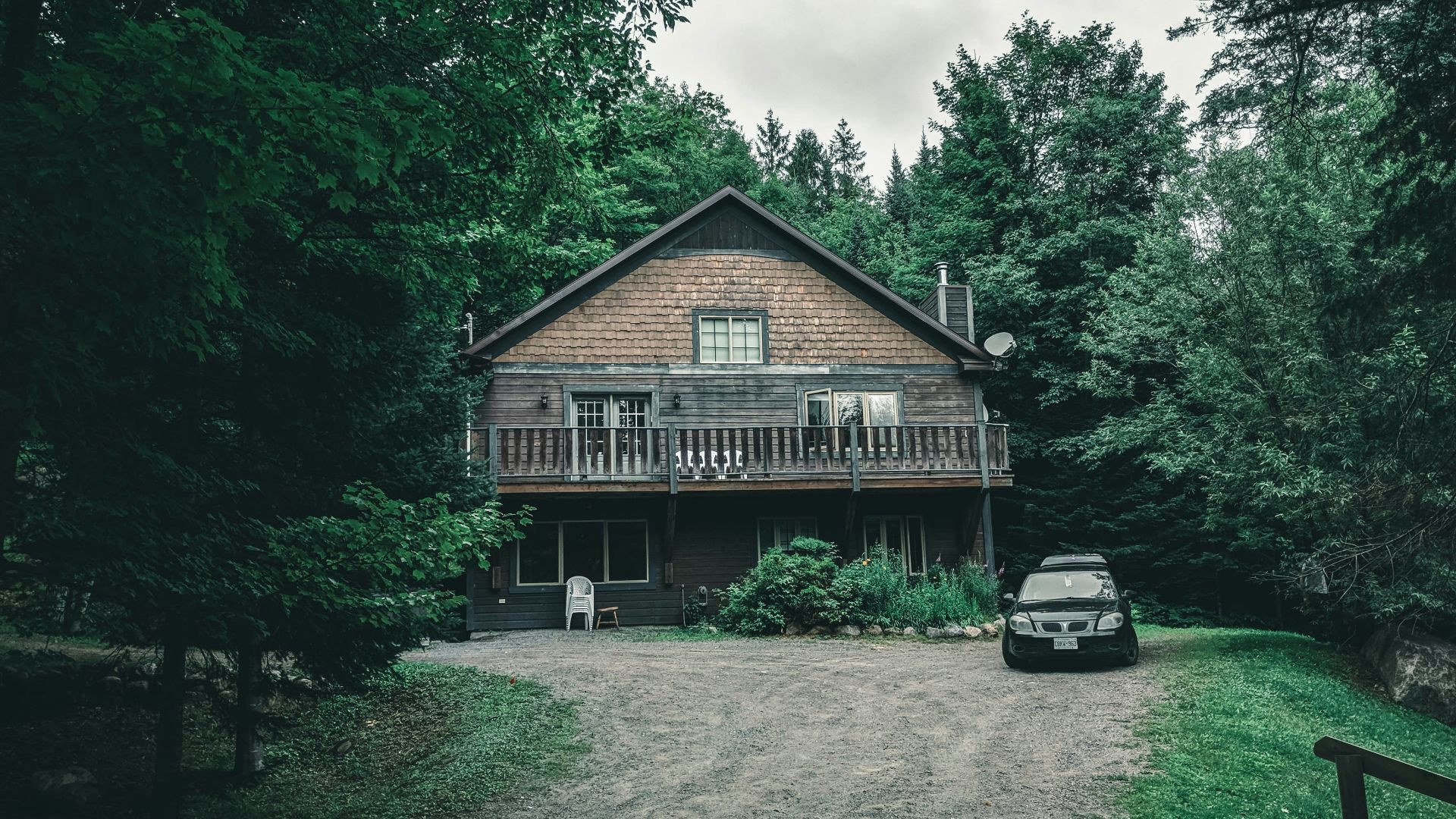 brown wooden house near green trees under white clouds during daytime