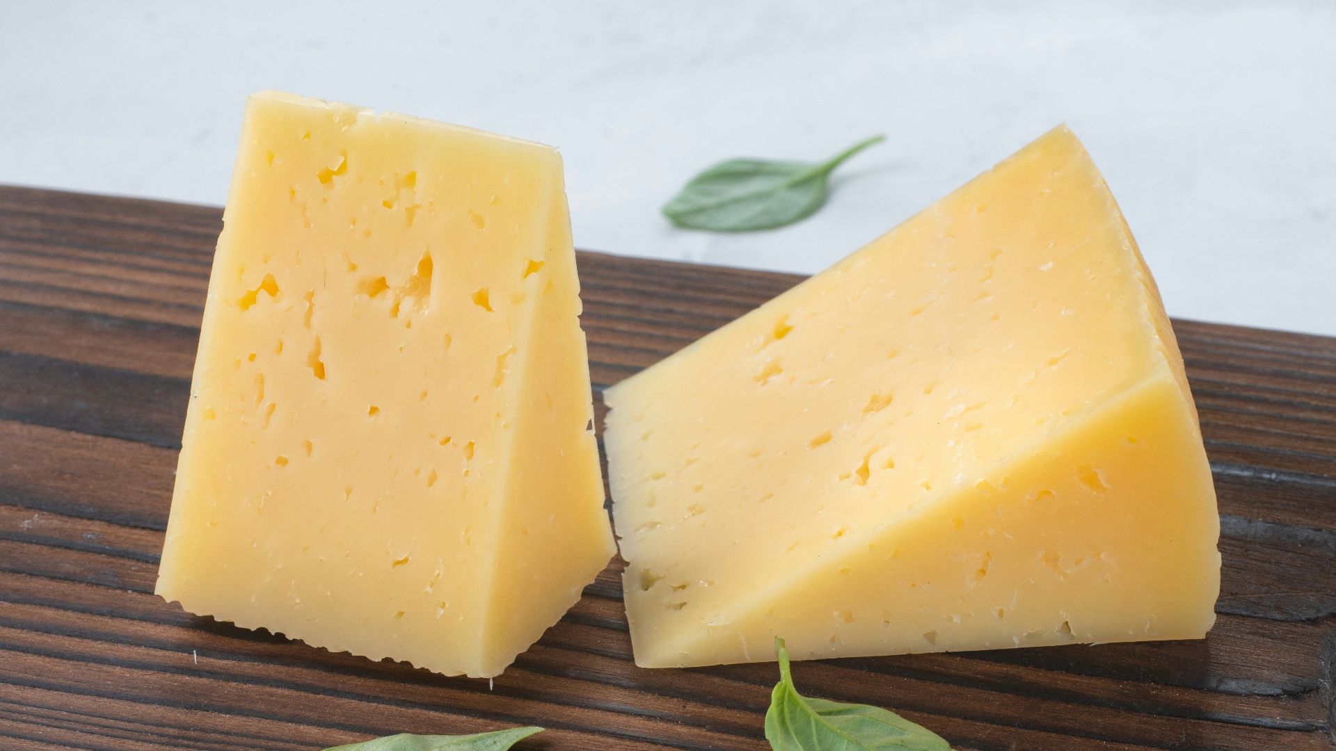a couple of pieces of cheese sitting on top of a wooden cutting board