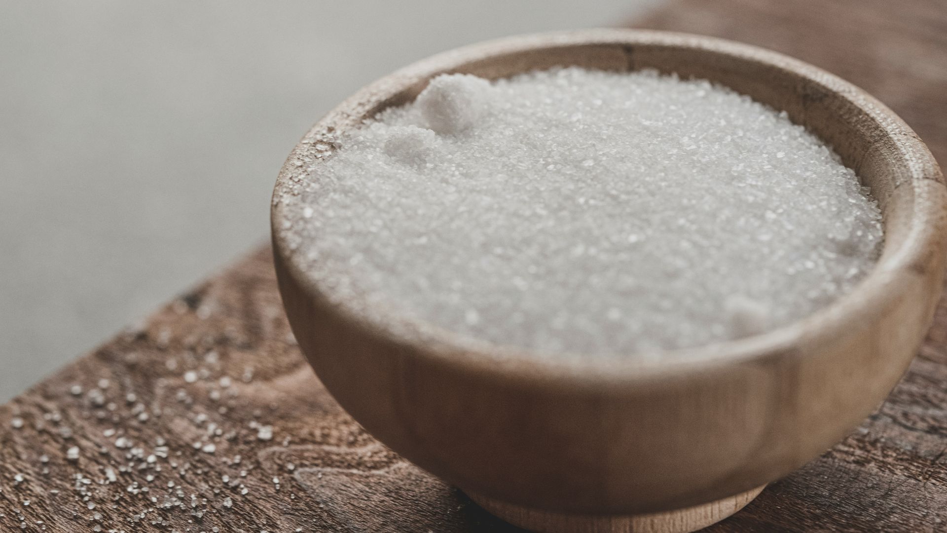 a wooden bowl filled with sugar on top of a wooden table