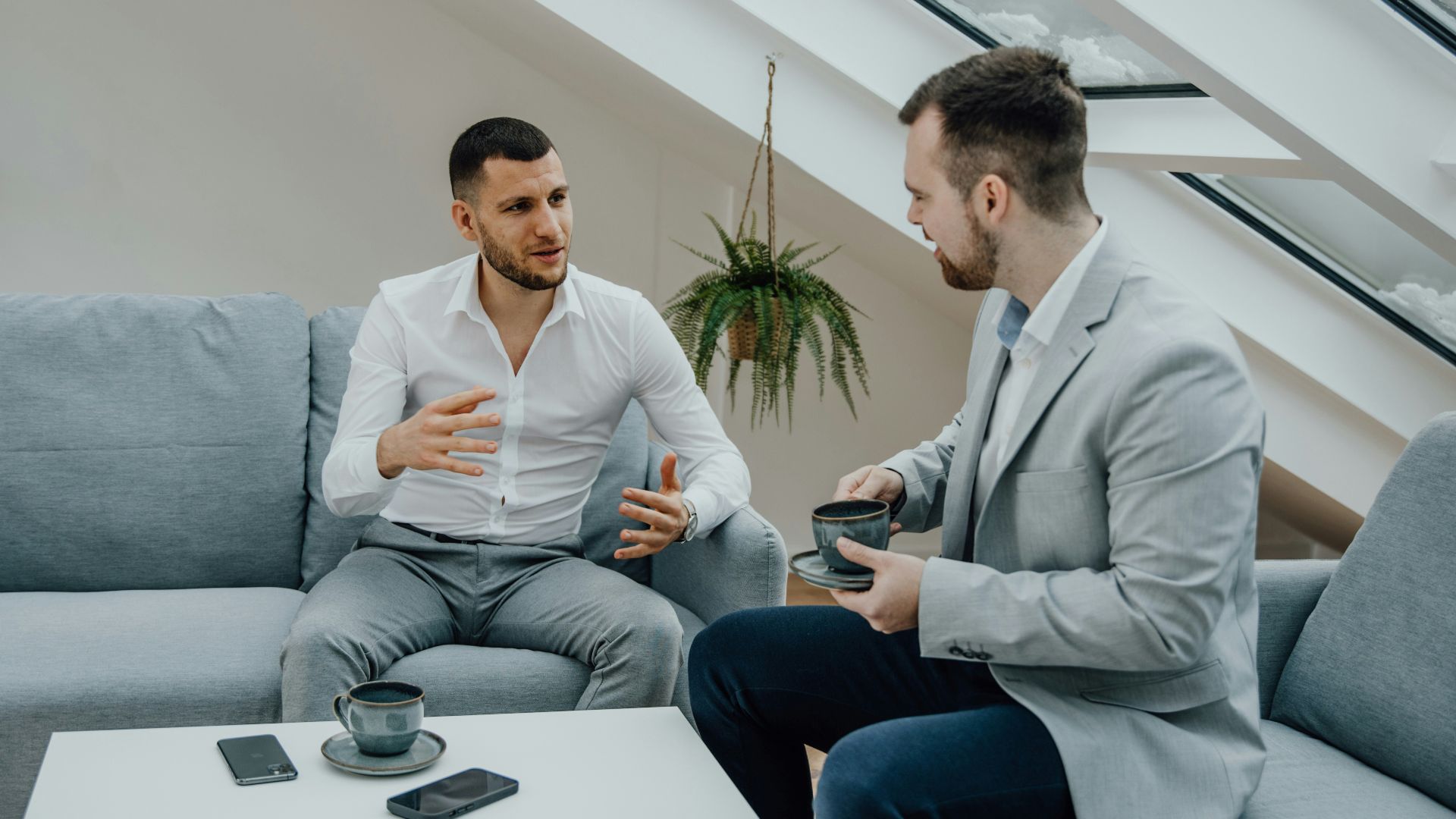 two men sitting on a couch talking to each other