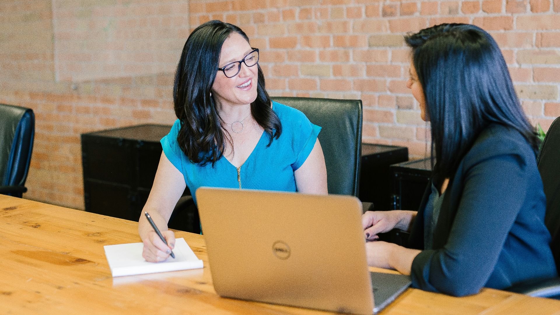 woman in teal t-shirt sitting beside woman in suit jacket