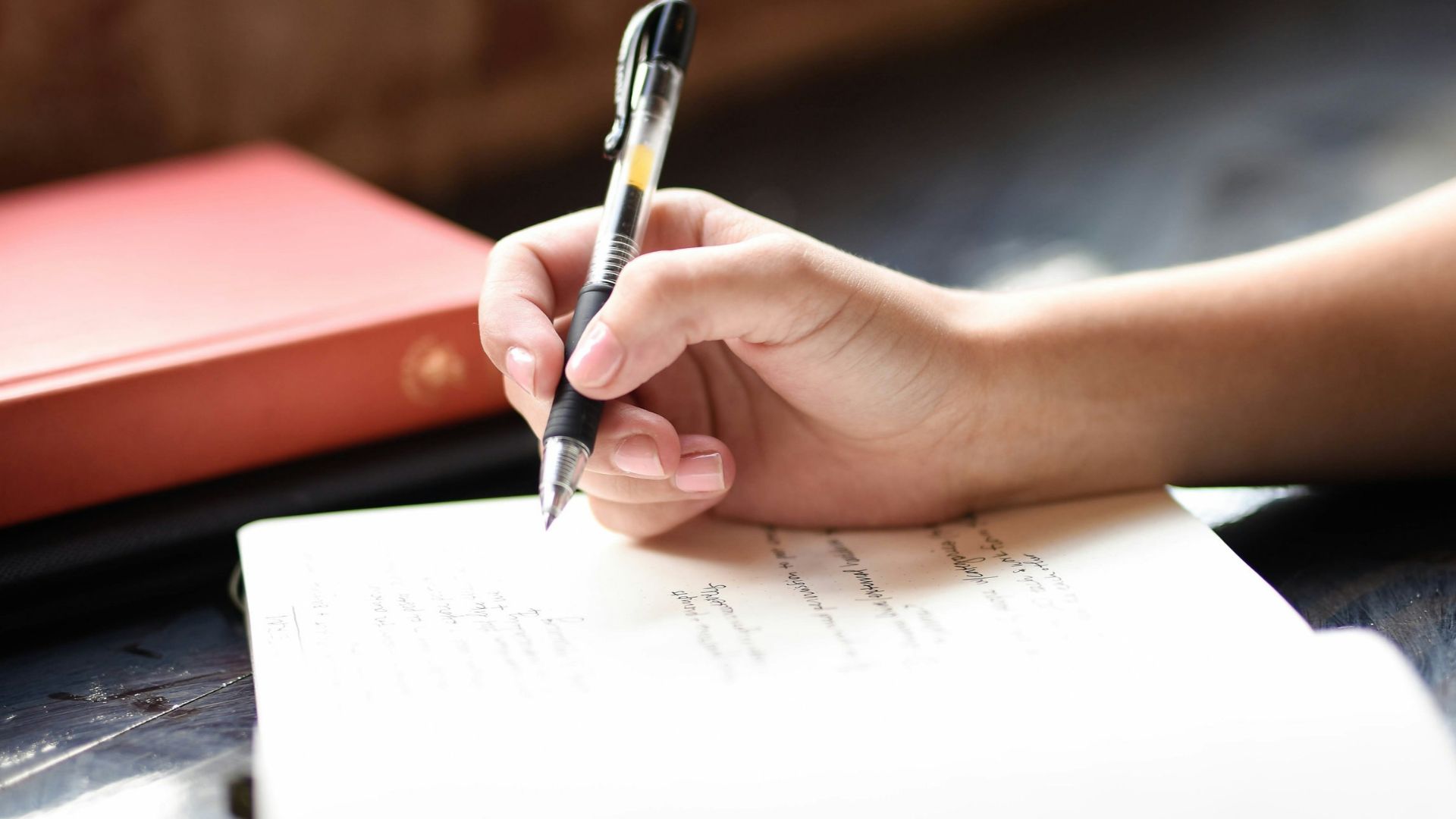 a person writing on a piece of paper with a pen