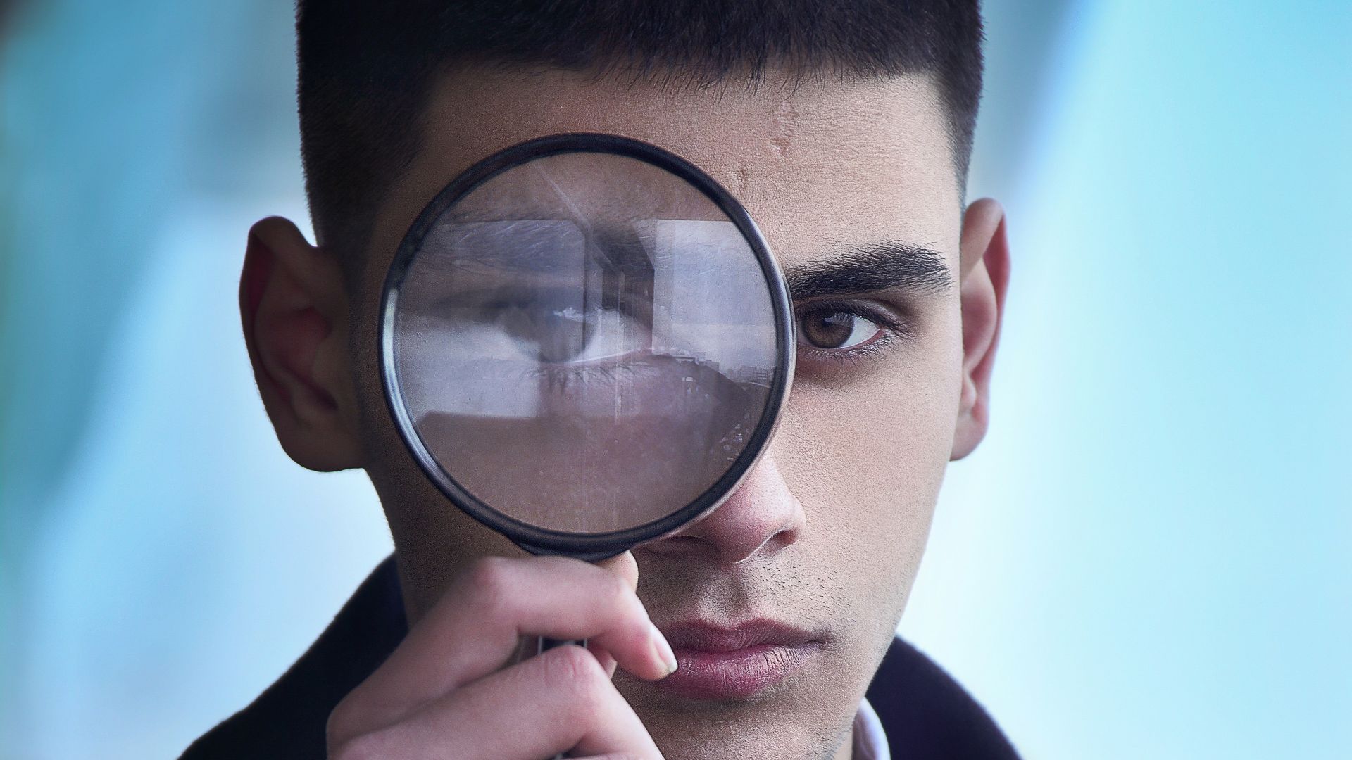 man in black suit holding magnifying glass
