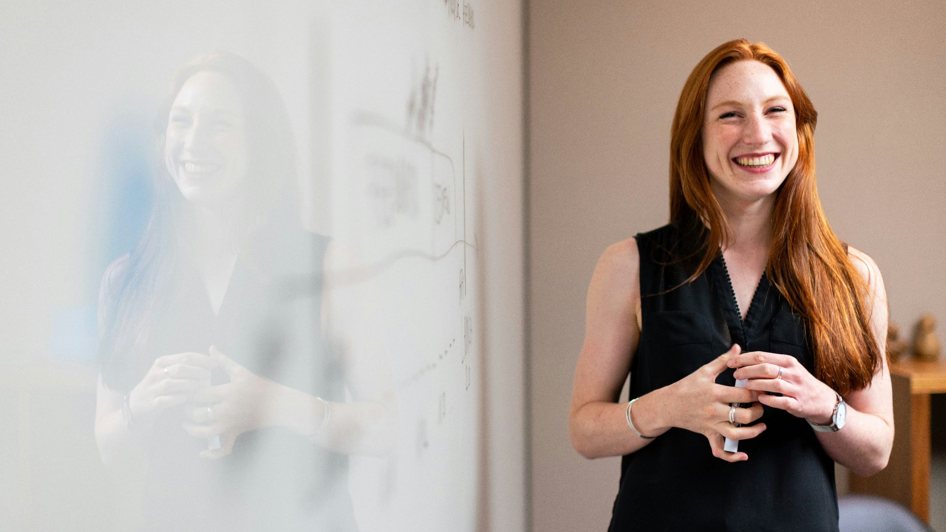 woman in blue tank top standing beside white wall