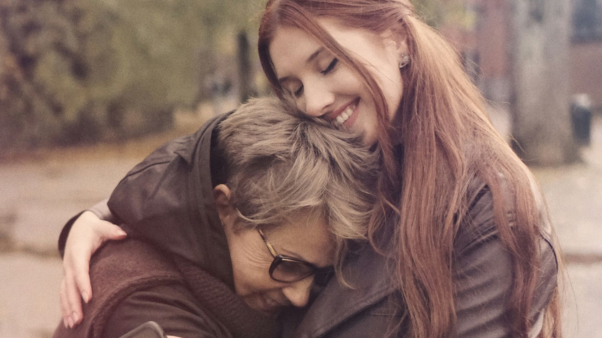 two women hugging each other on a city street