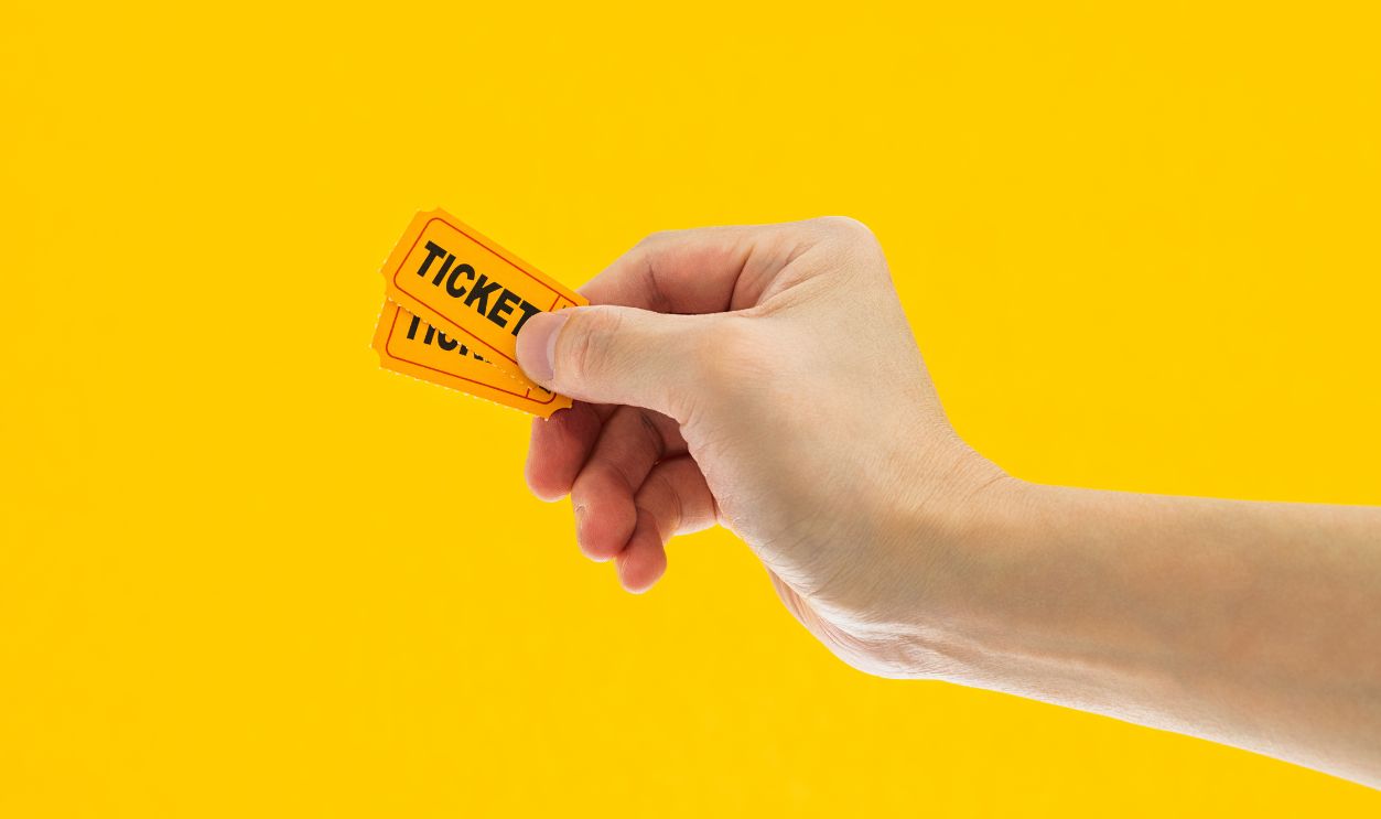 Hand holding two cinema tickets on yellow background - stock photo