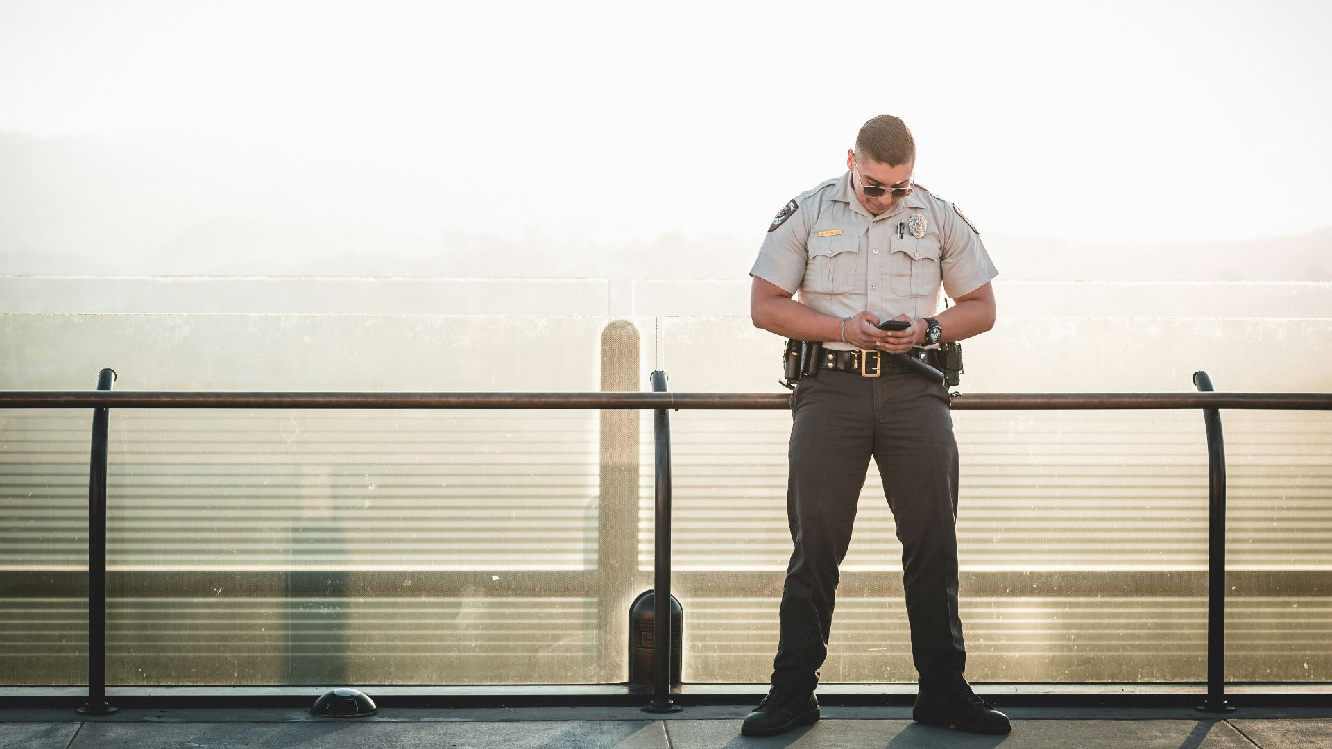 cop leaning on metal rail during a sunny day