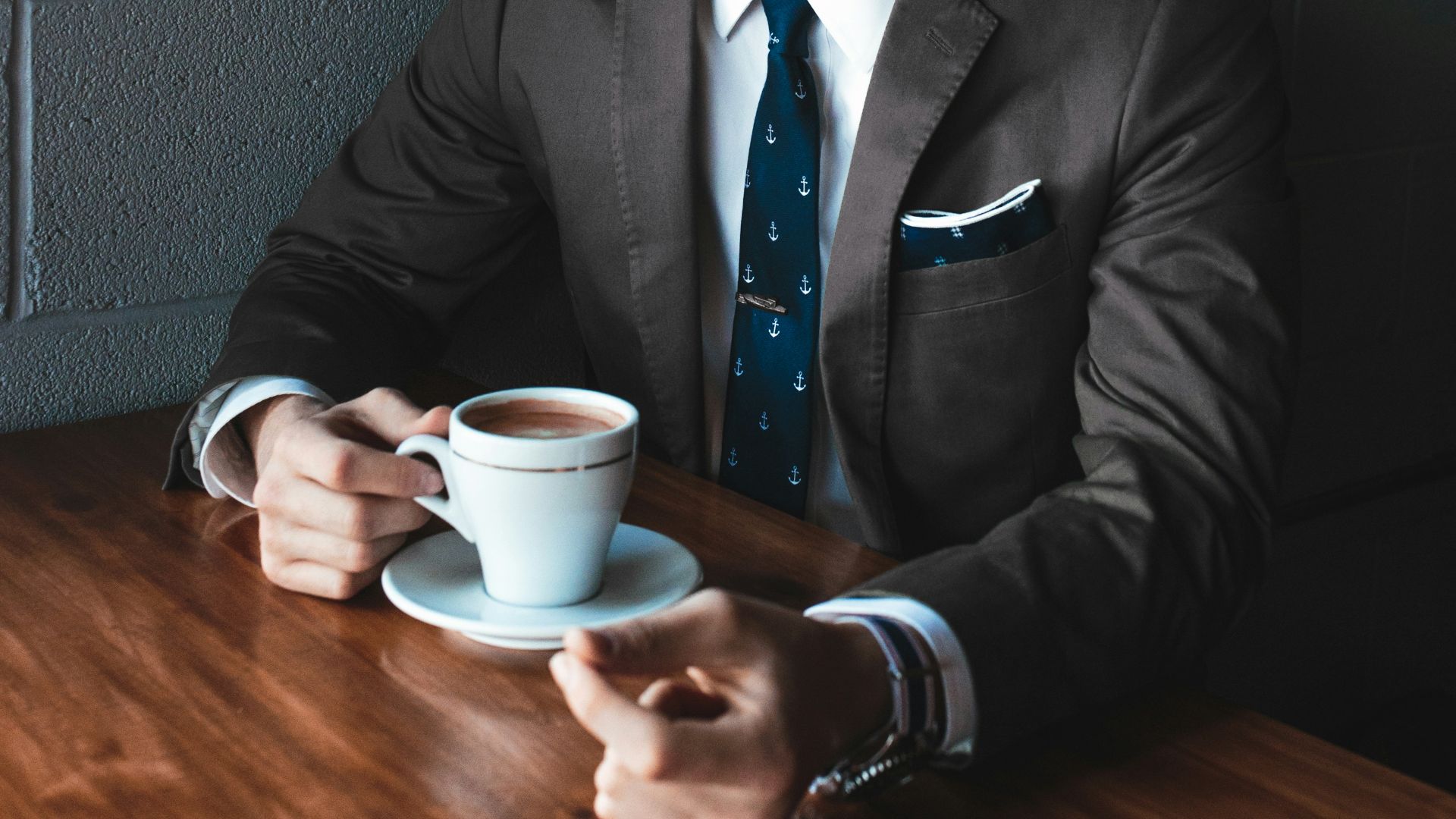 man holding cup filled with coffee on table