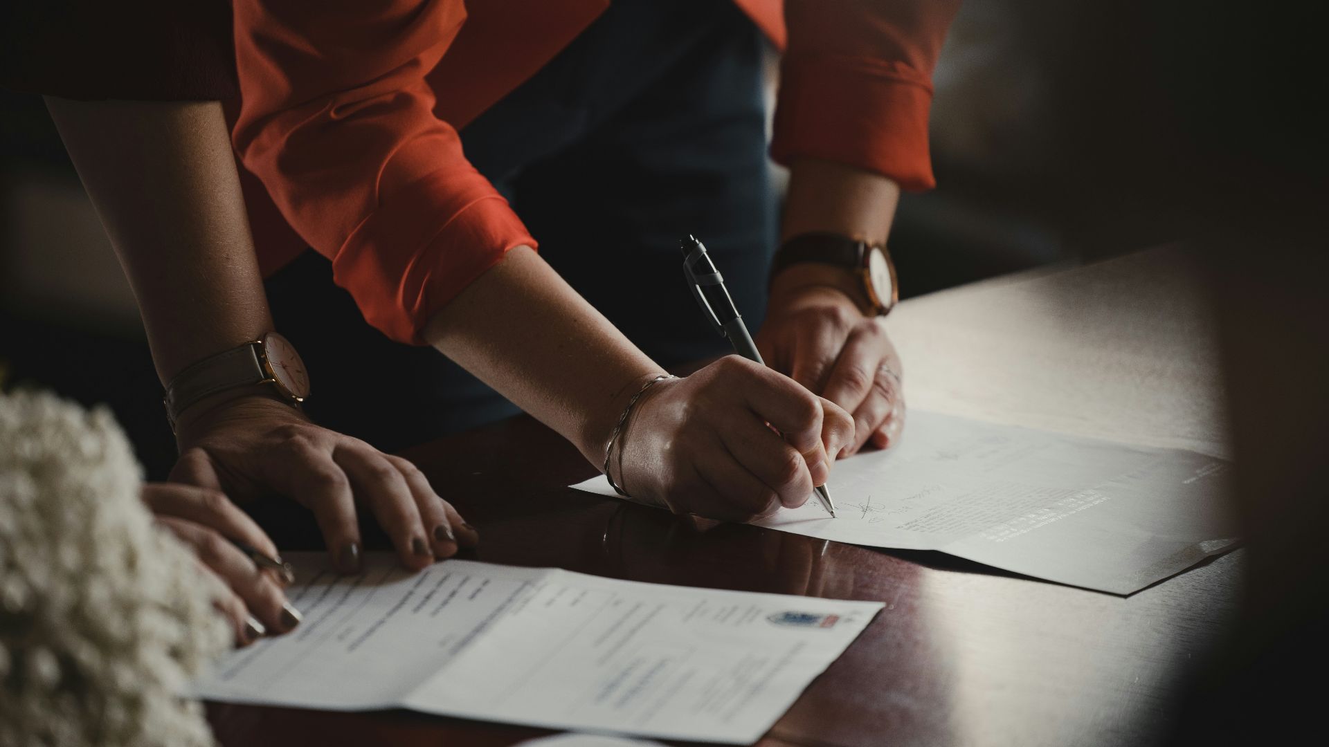 person in orange long sleeve shirt writing on white paper