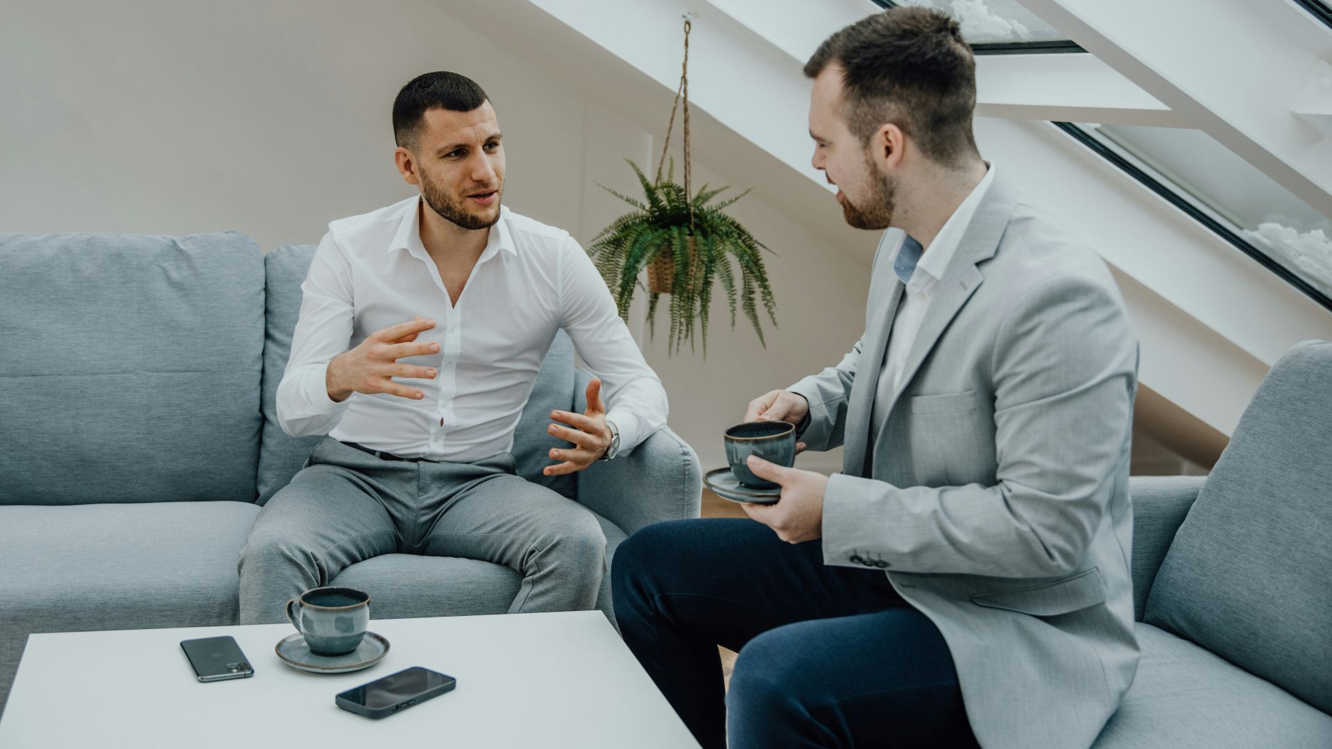 two men sitting on a couch talking to each other