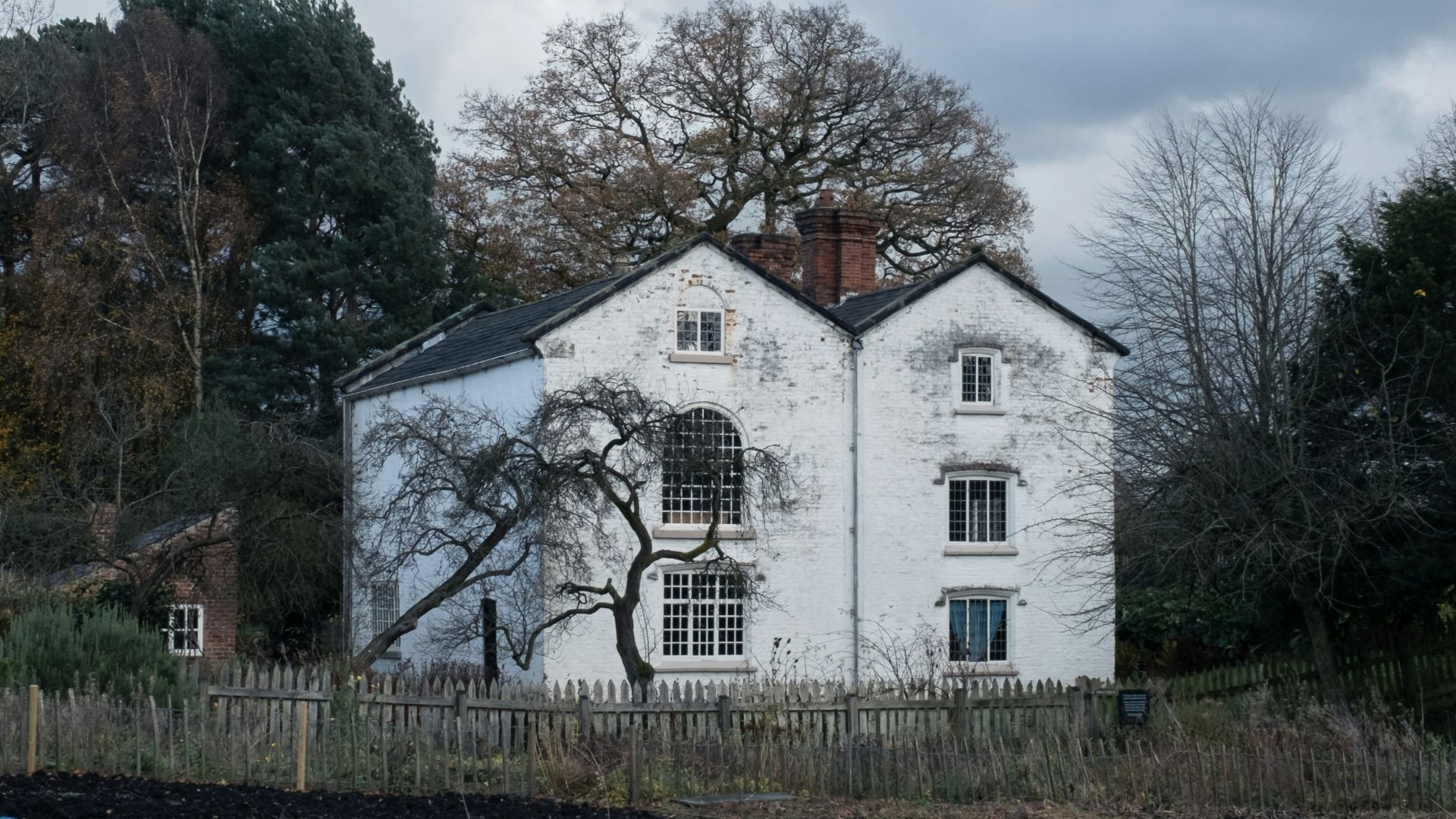 white and brown house surrounded by trees under white clouds during daytime