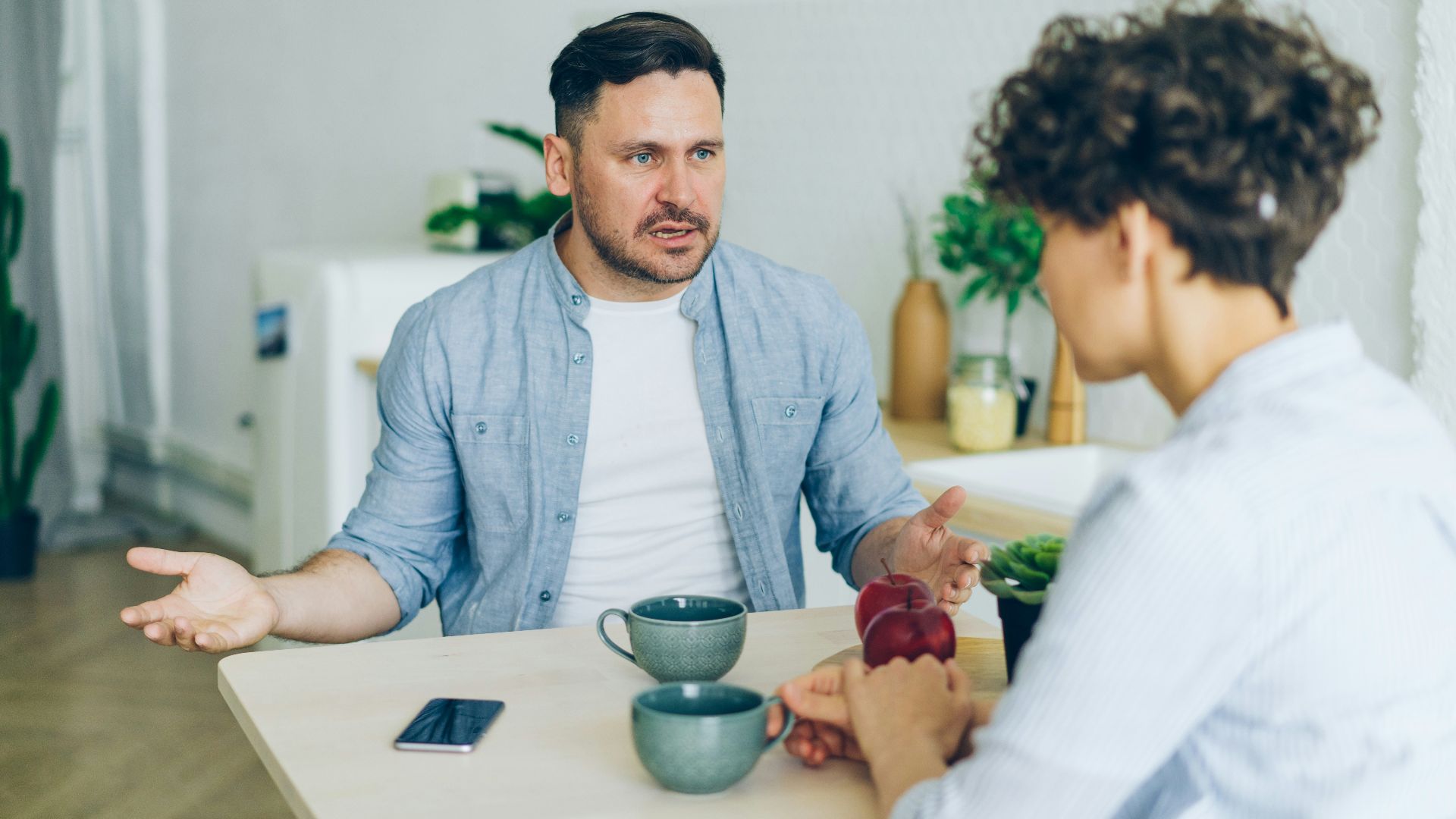 a man sitting at a table talking to a woman