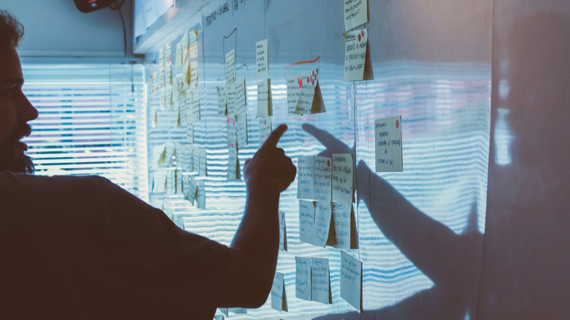 person pointing white paper on wall