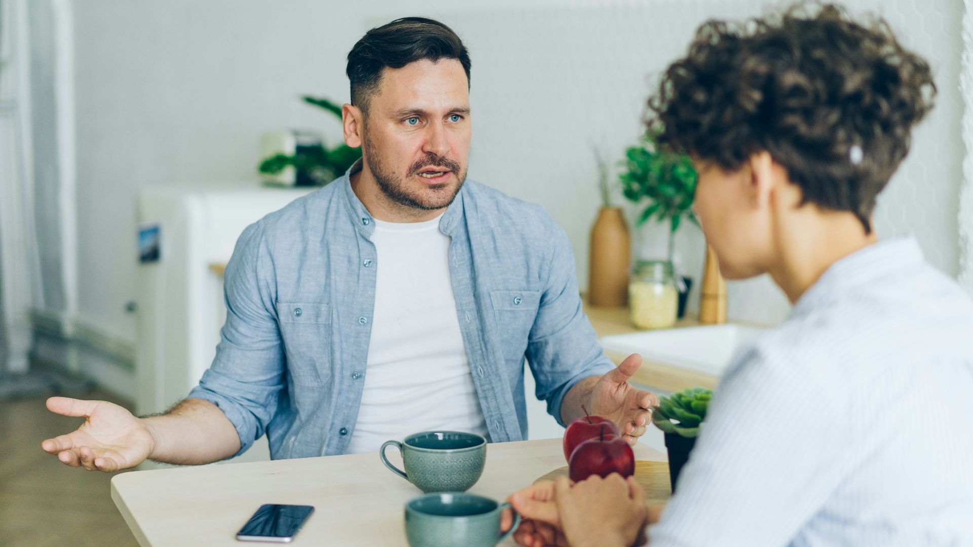 a man sitting at a table talking to a woman