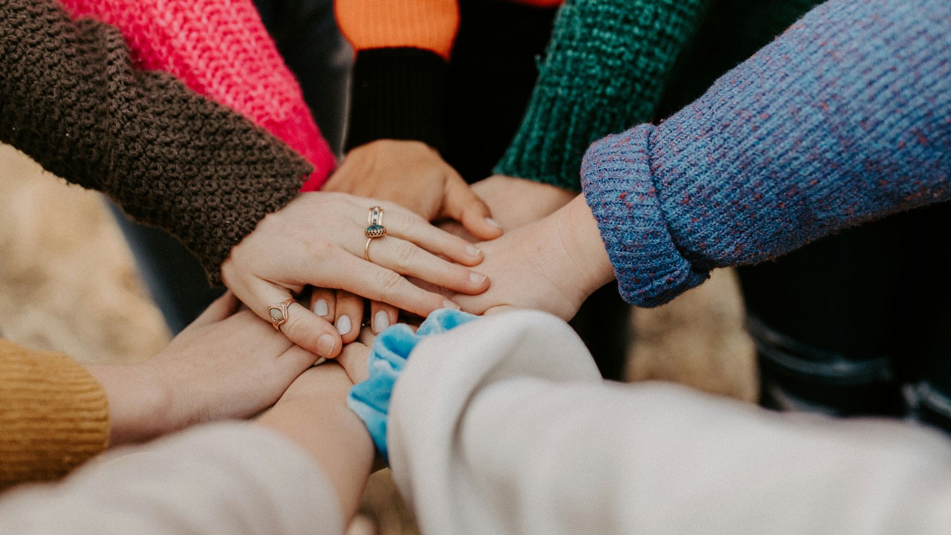 person in red sweater holding babys hand