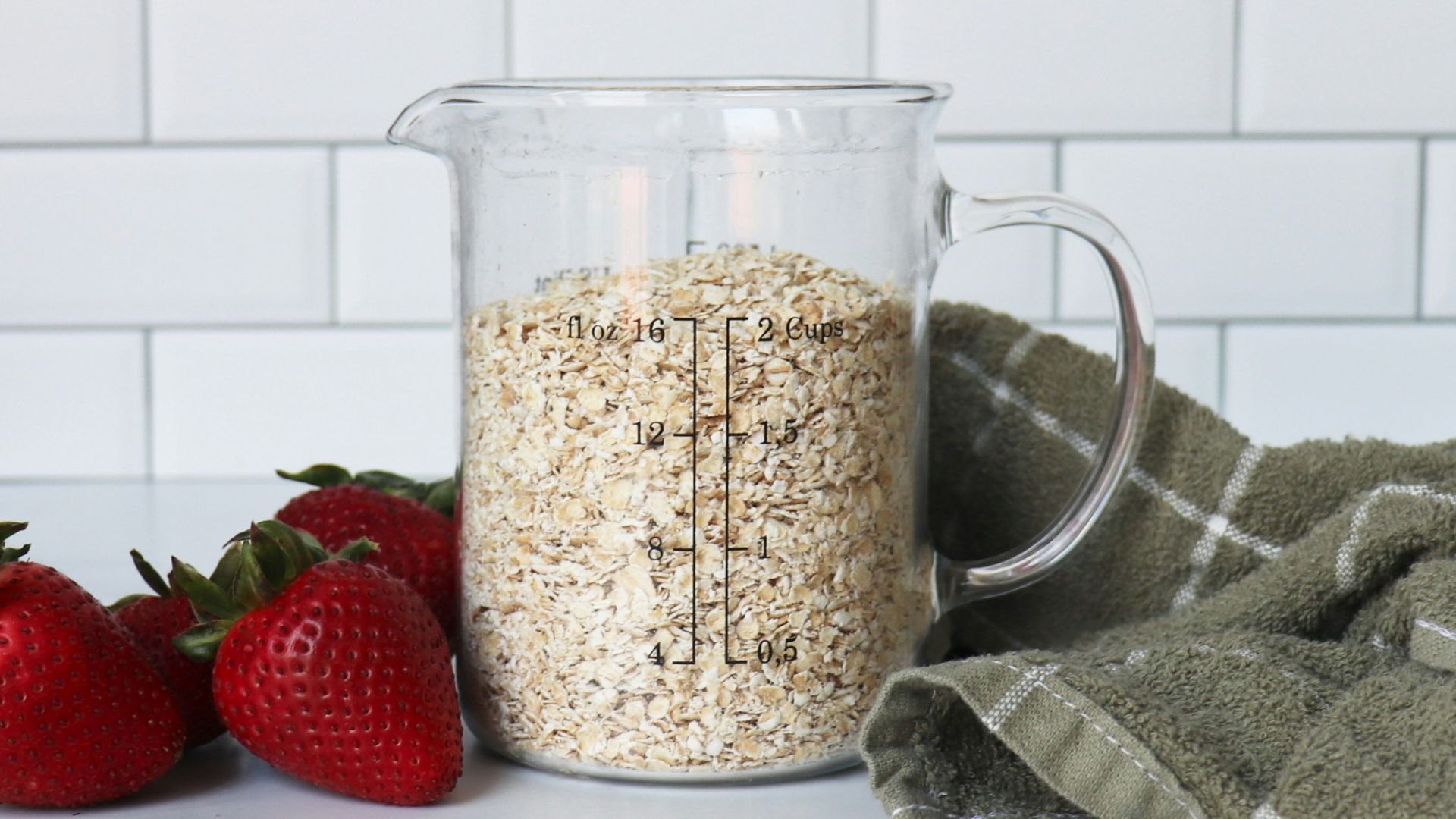 strawberries on white ceramic bowl beside clear glass pitcher