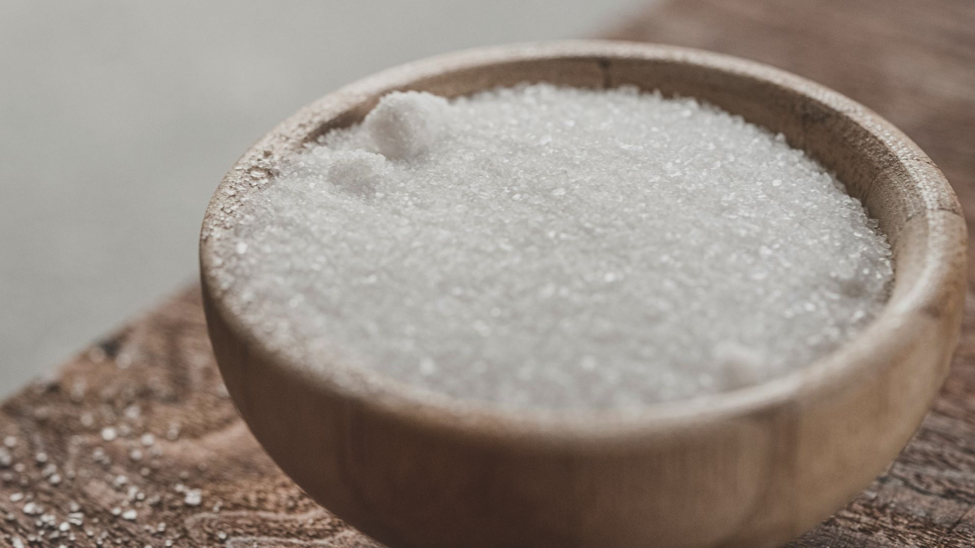 a wooden bowl filled with sugar on top of a wooden table
