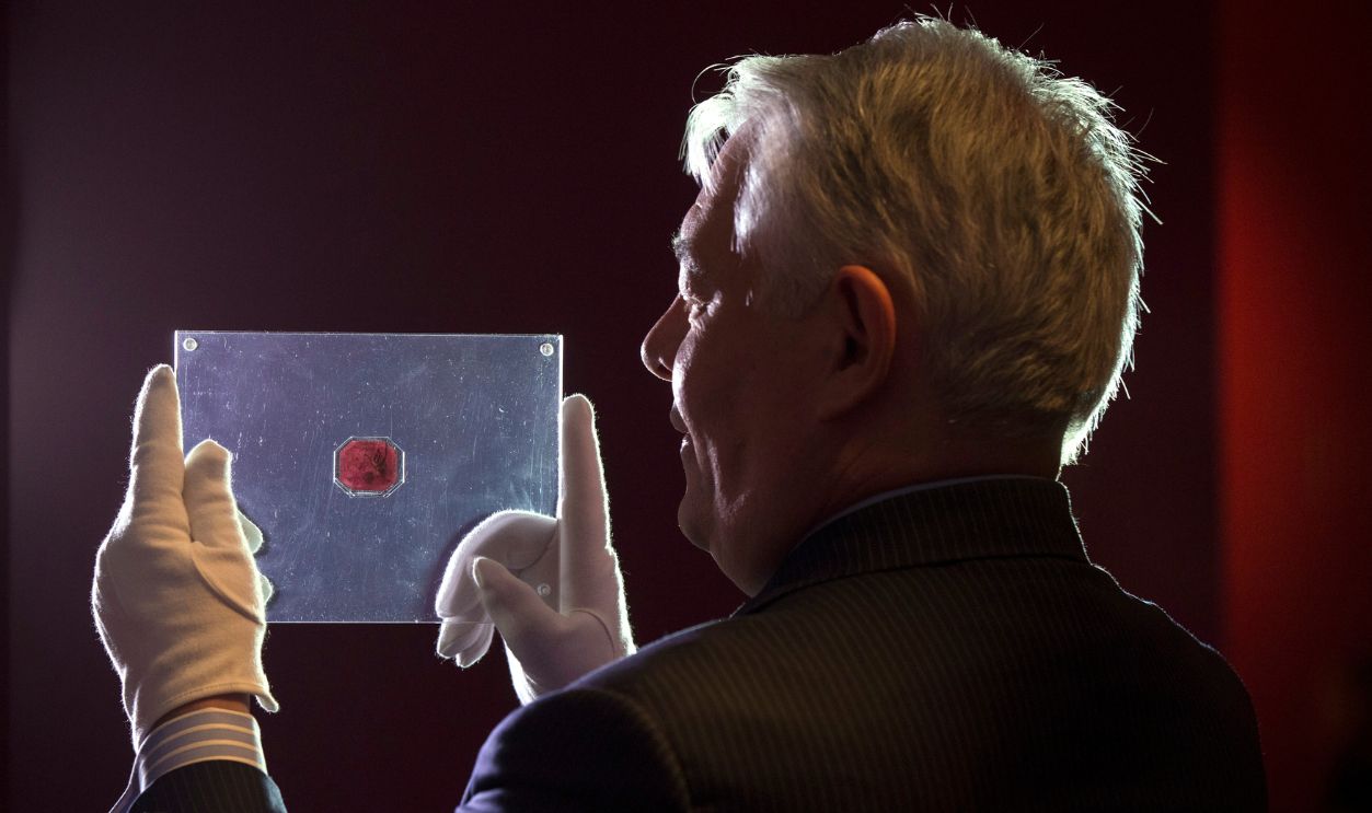 LONDON, ENGLAND - JUNE 02: An employee of Sotheby's auction house holds a case containing the sole-surviving 'British Guiana One-Cent Magenta' stamp dating from 1856, on June 2, 2014 in London, England. The unique stamp is expected to fetch 20 million USD when auctioned in New York, USA on June 17, 2014. The stamp was initially discovered in 1873 by a 12-year old Scottish boy living in British Guiana, South America who sold it to a local stamp collector for several shillings