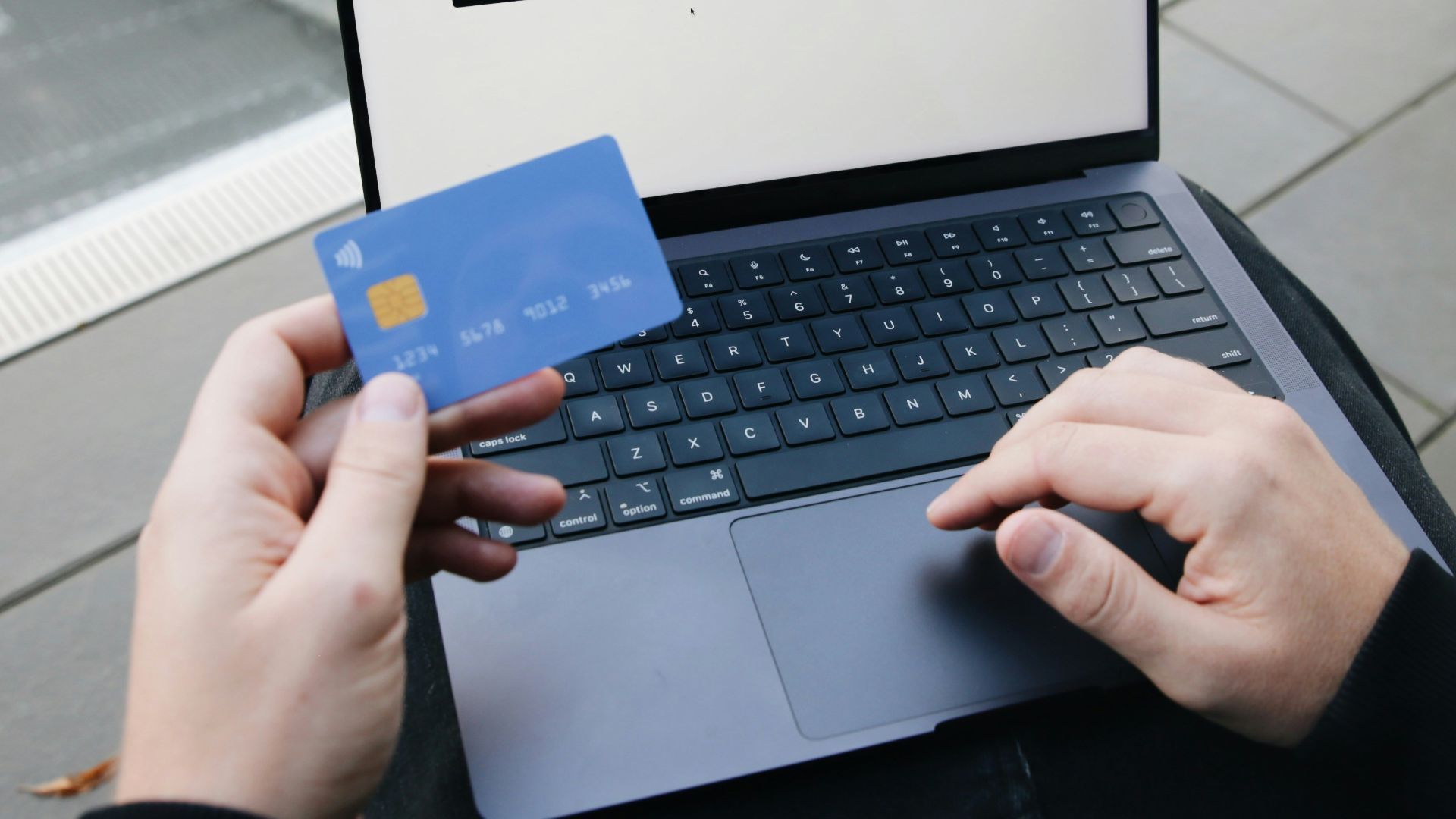A person sitting in a chair with a laptop and a credit card