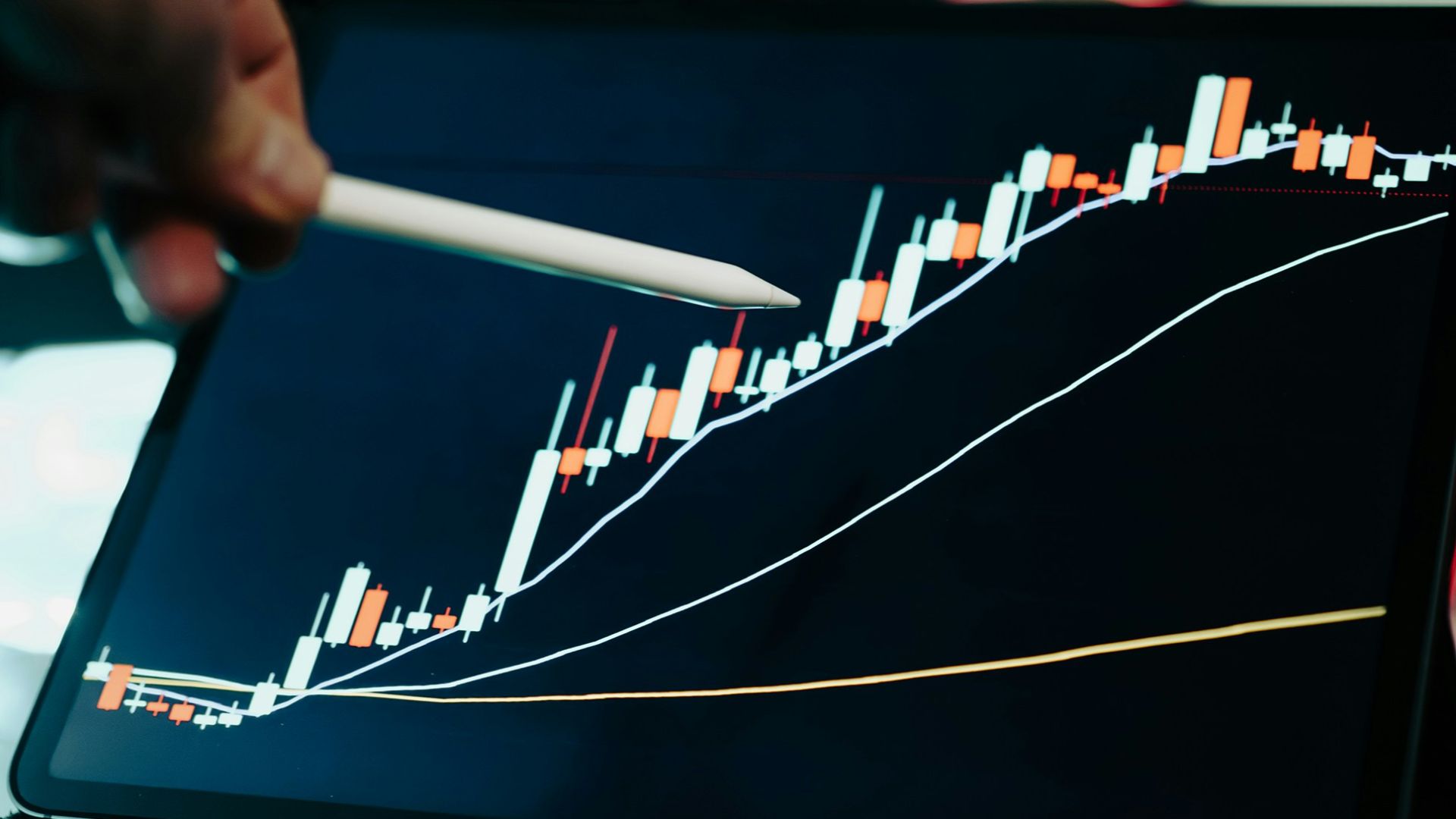 A person pointing at a chart on a laptop