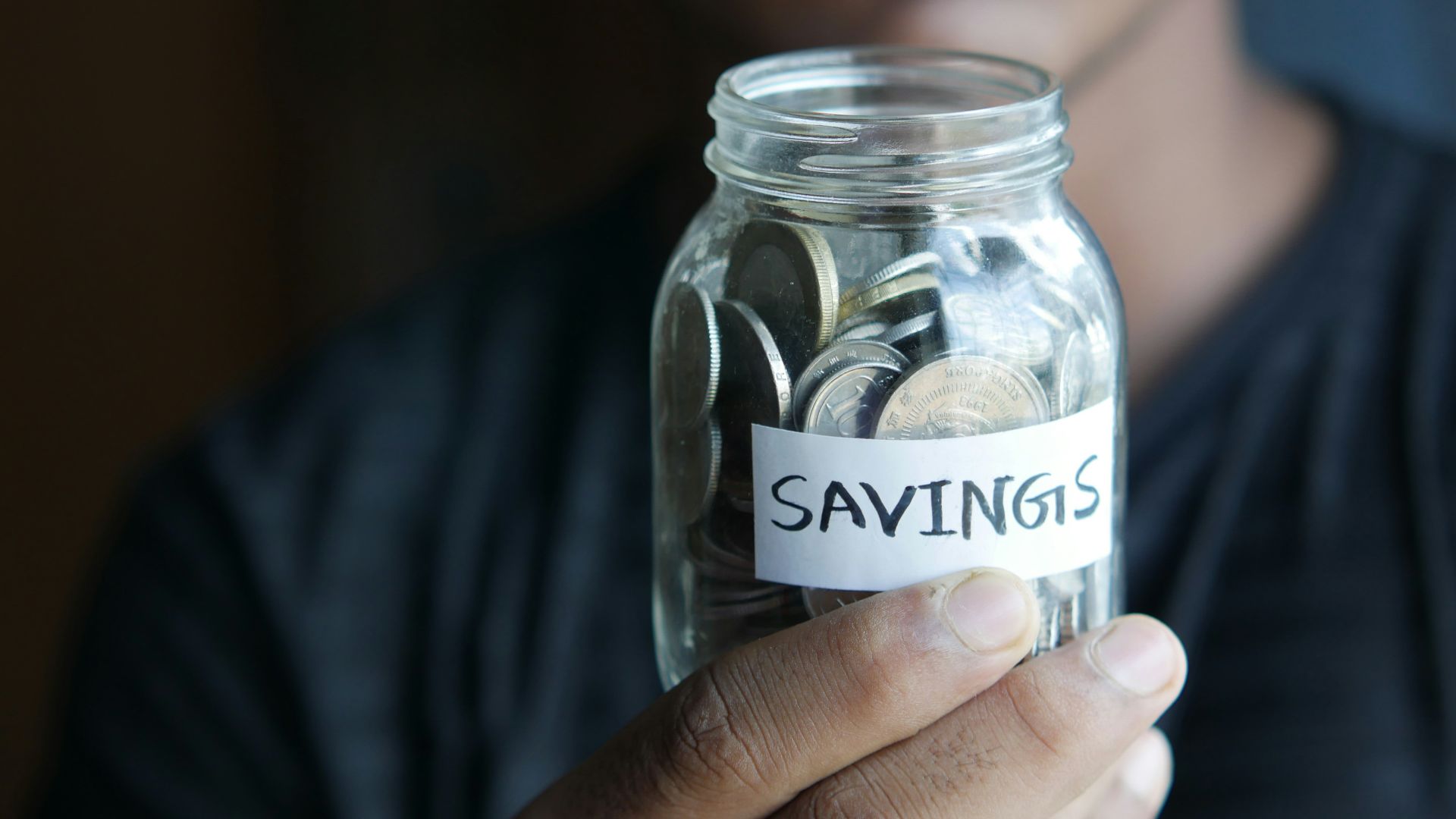 a man holding a jar with a savings label on it