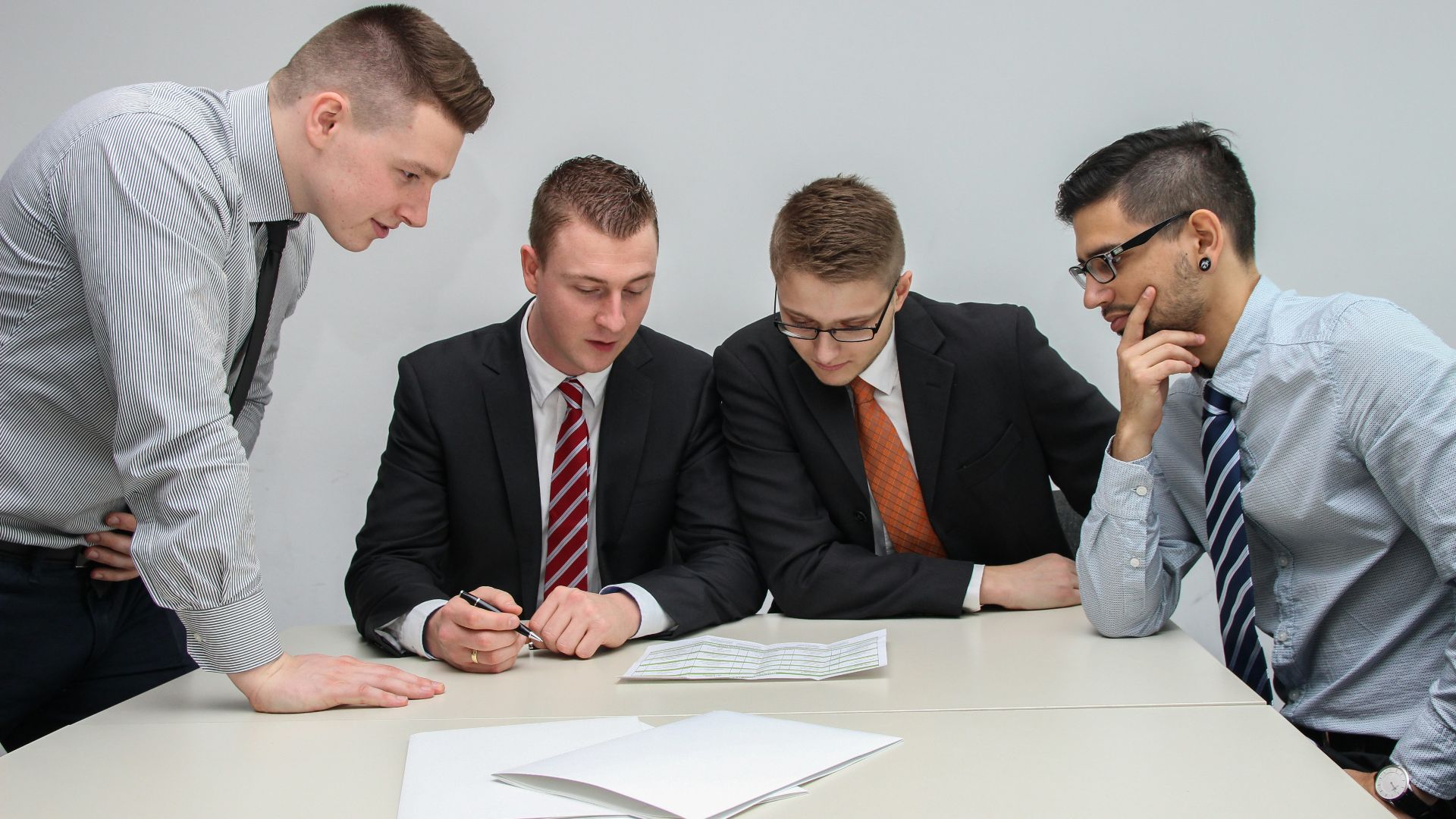 four men looking to the paper on table