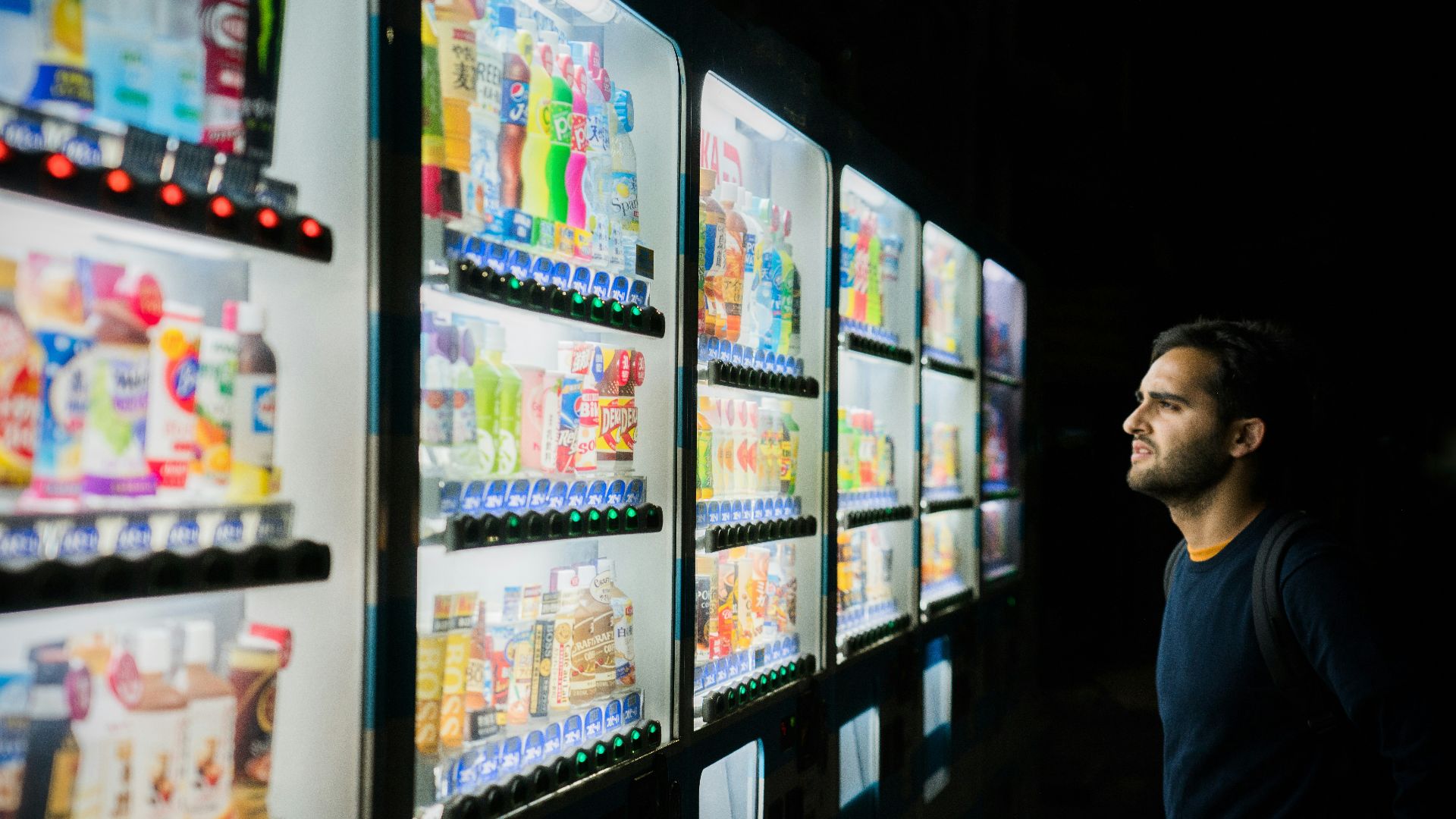 man on front of vending machines at nighttime