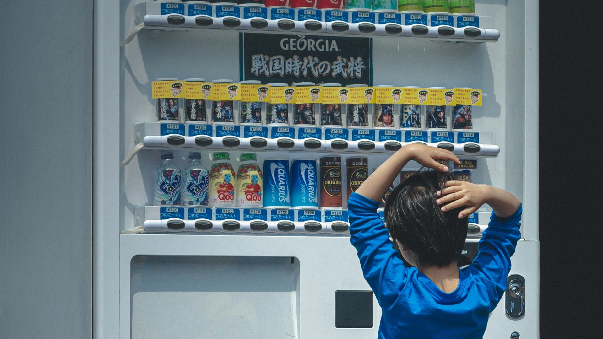 a young boy standing in front of a vending machine