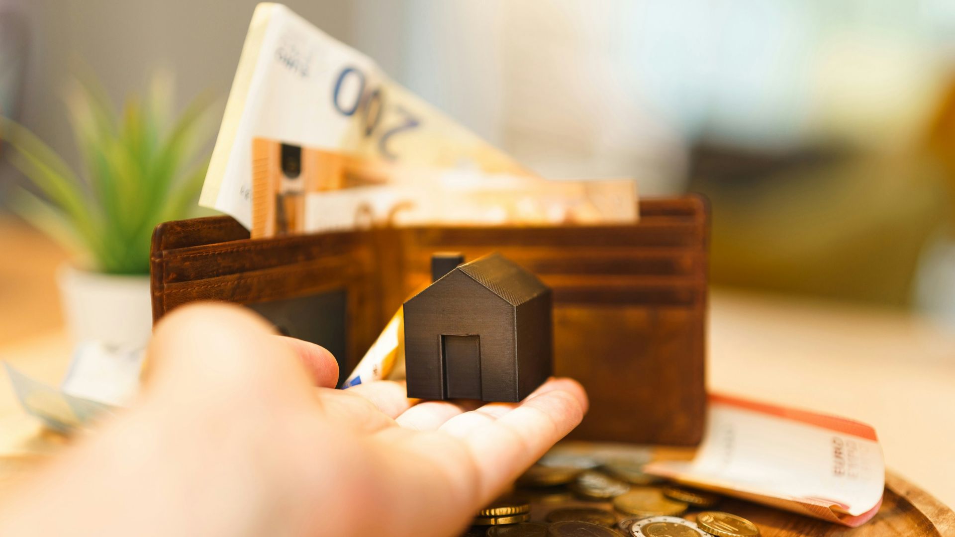 A person holding a small house and some money