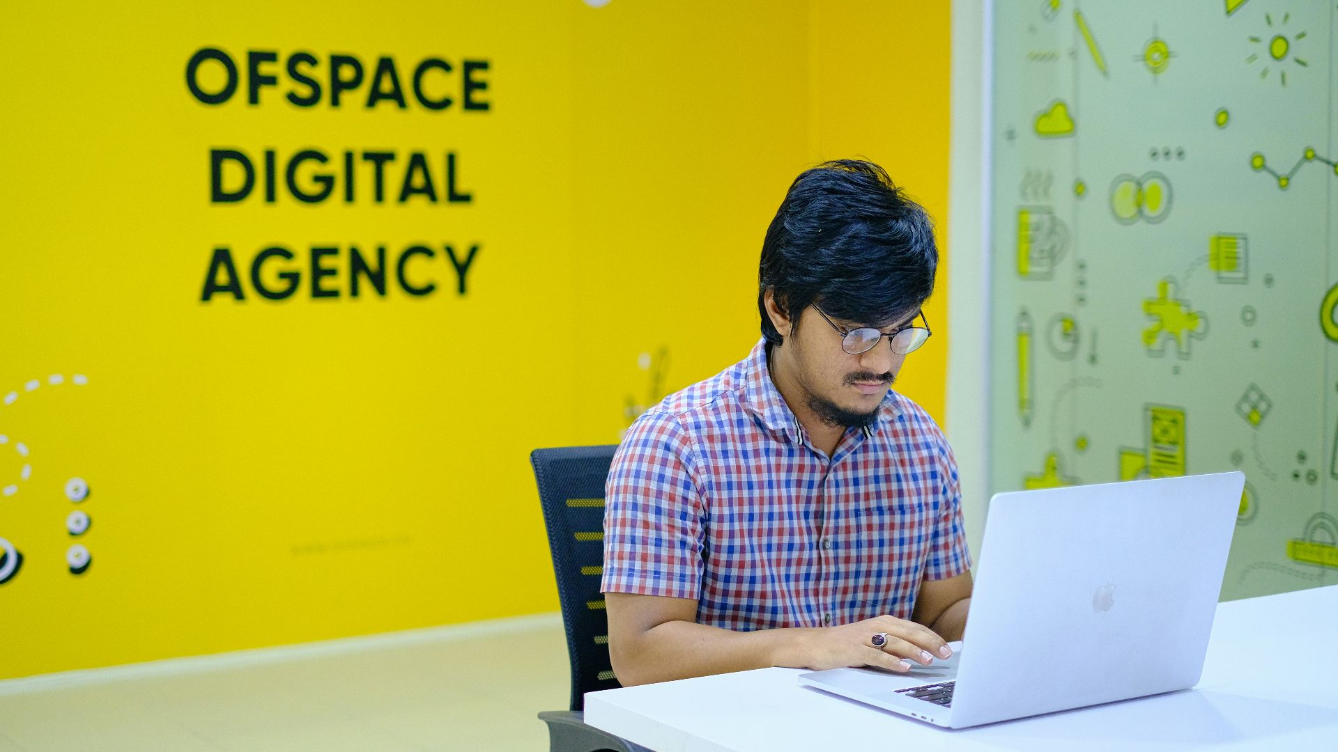 man in blue and white checkered dress shirt sitting on black chair
