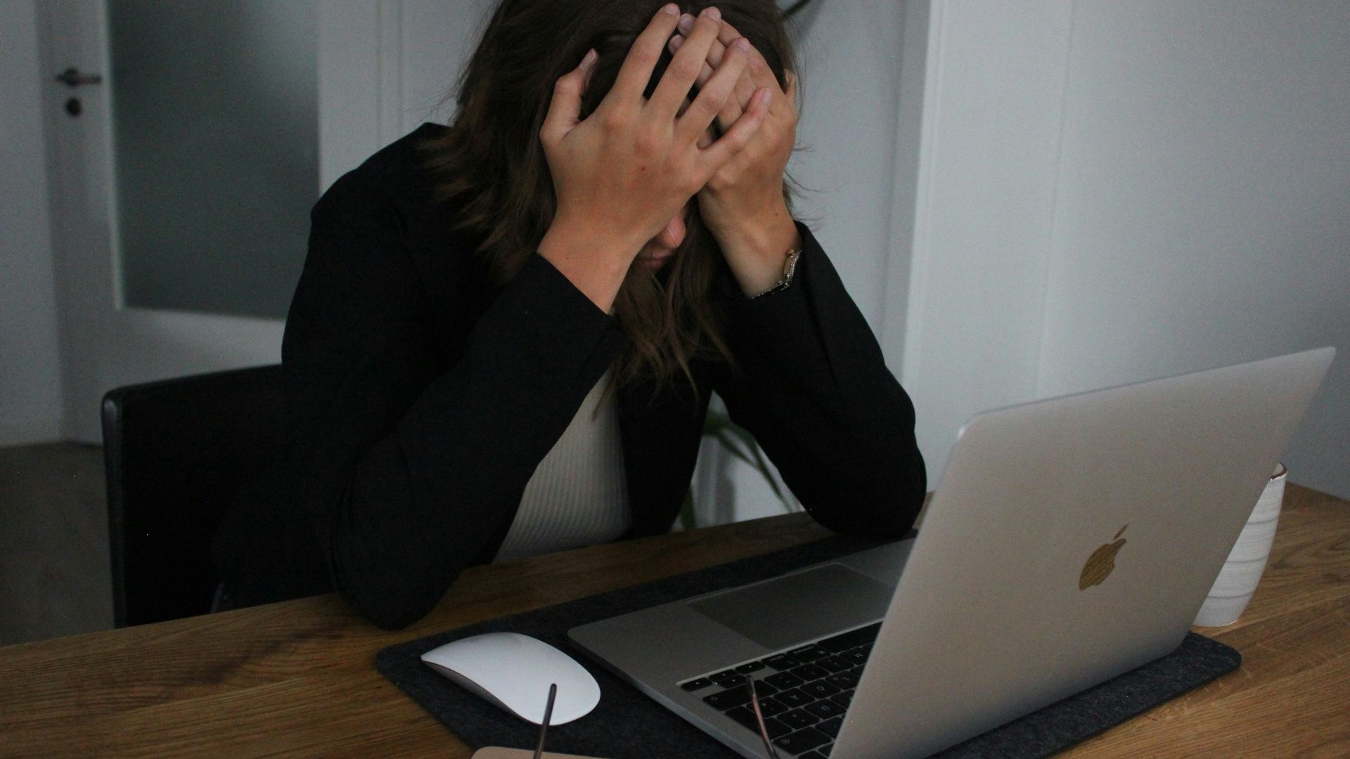 a woman covering her face while looking at a laptop