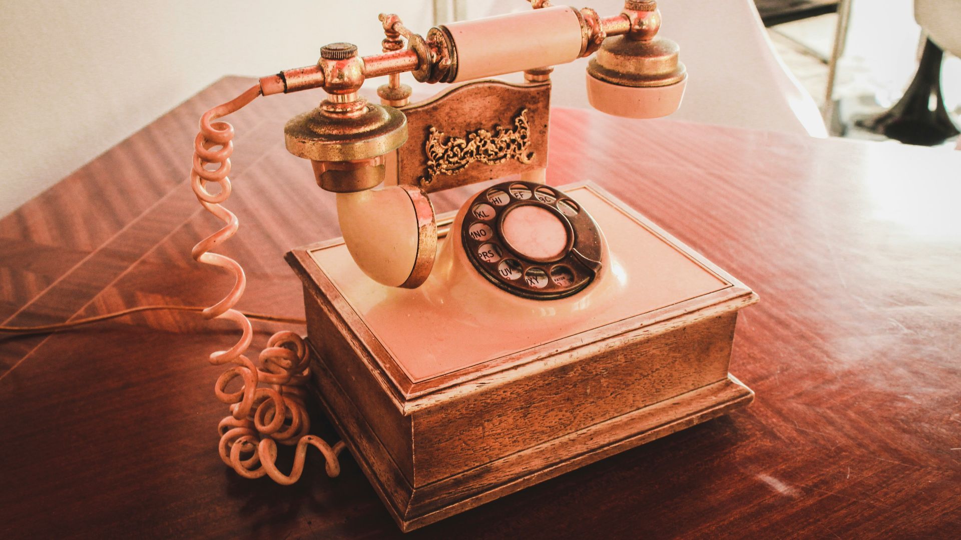 white and brown rotary telephone on brown wooden table