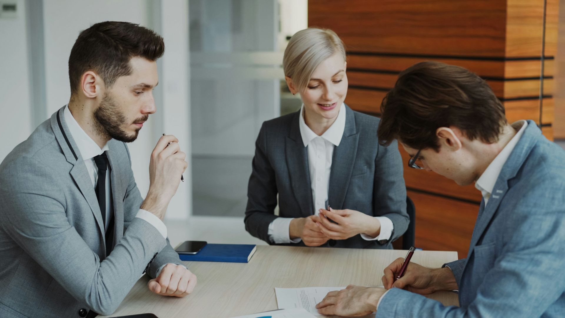 Business people signing a contract at a table.