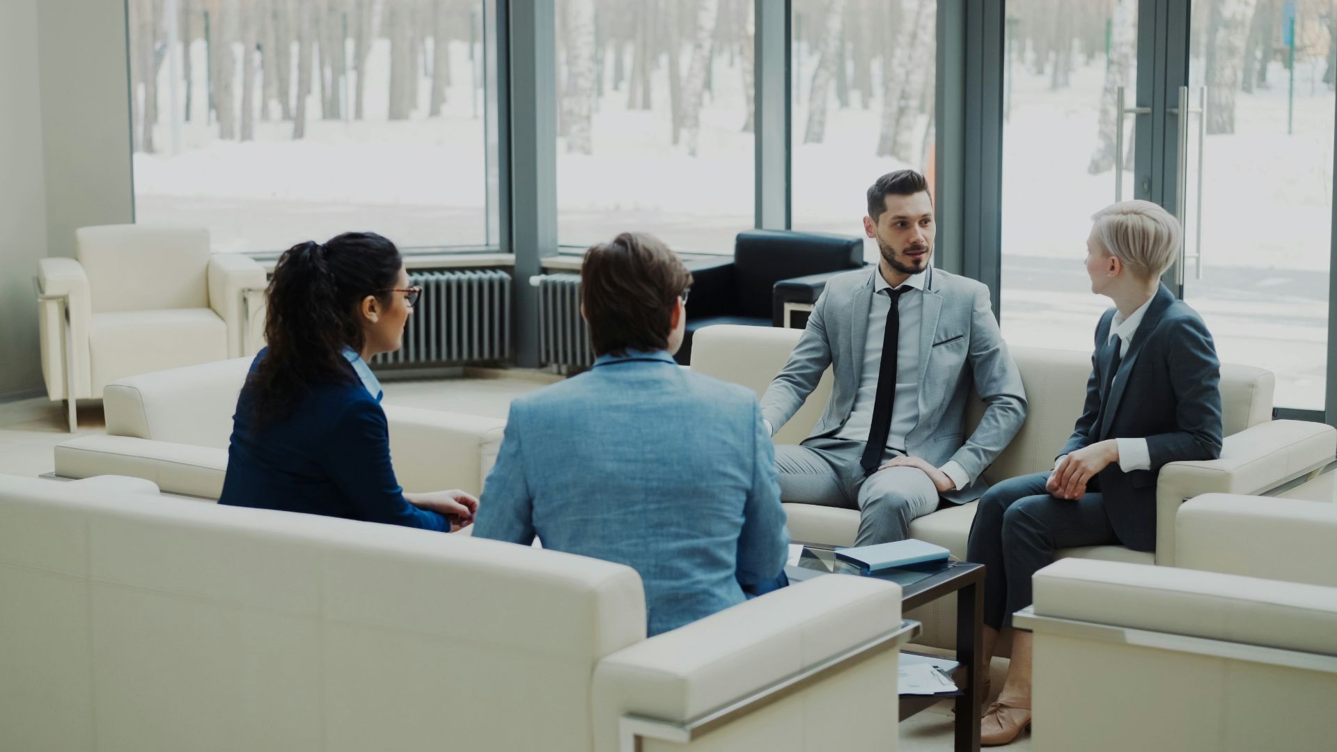 Four professionals in a modern office meeting space.