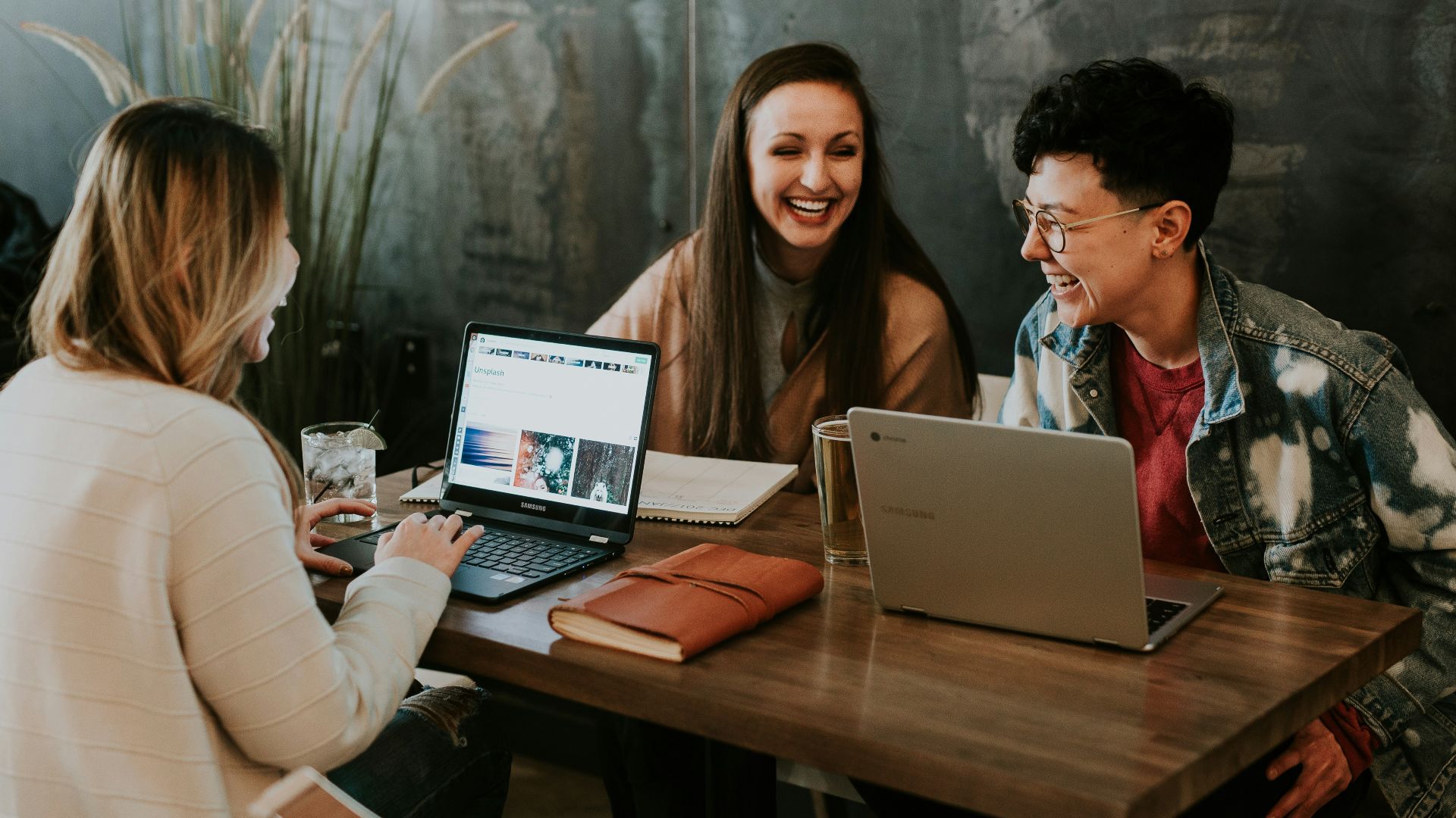 three people sitting in front of table laughing together