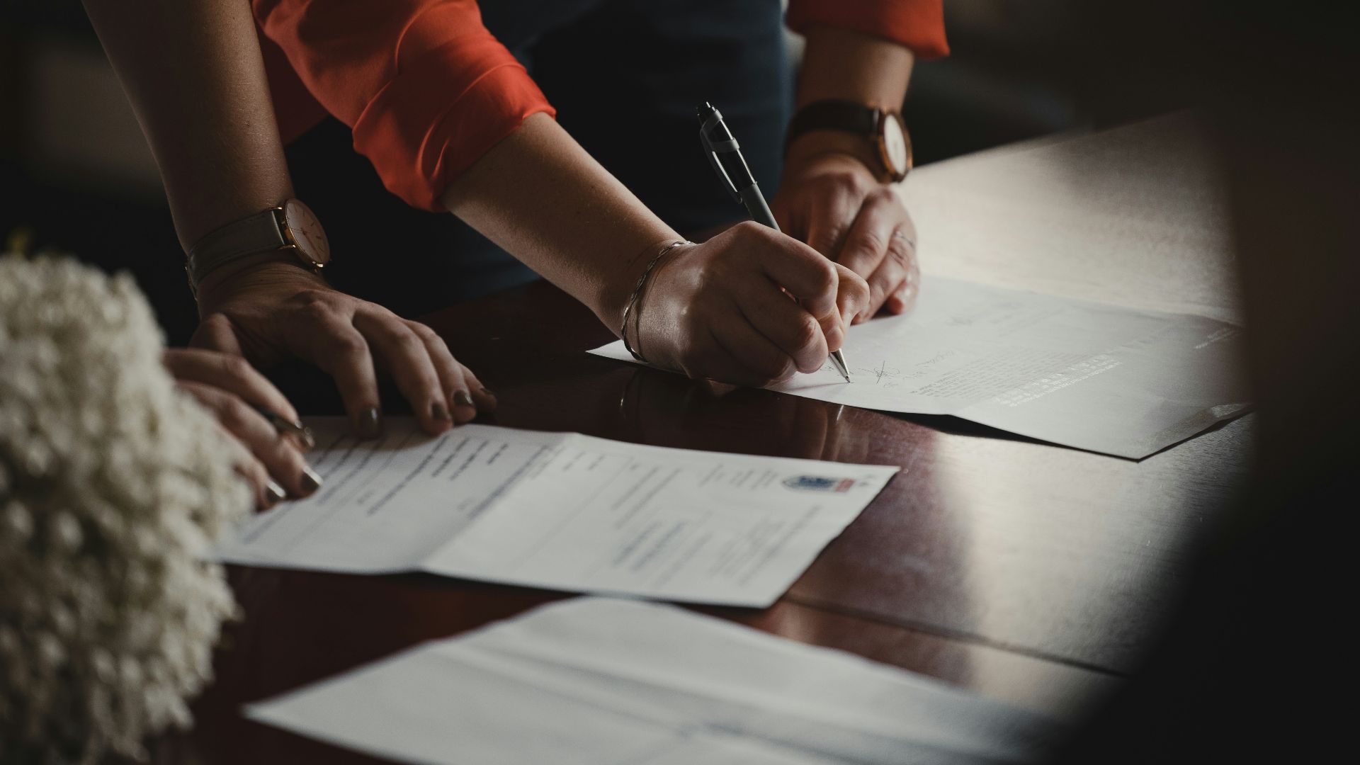 person in orange long sleeve shirt writing on white paper