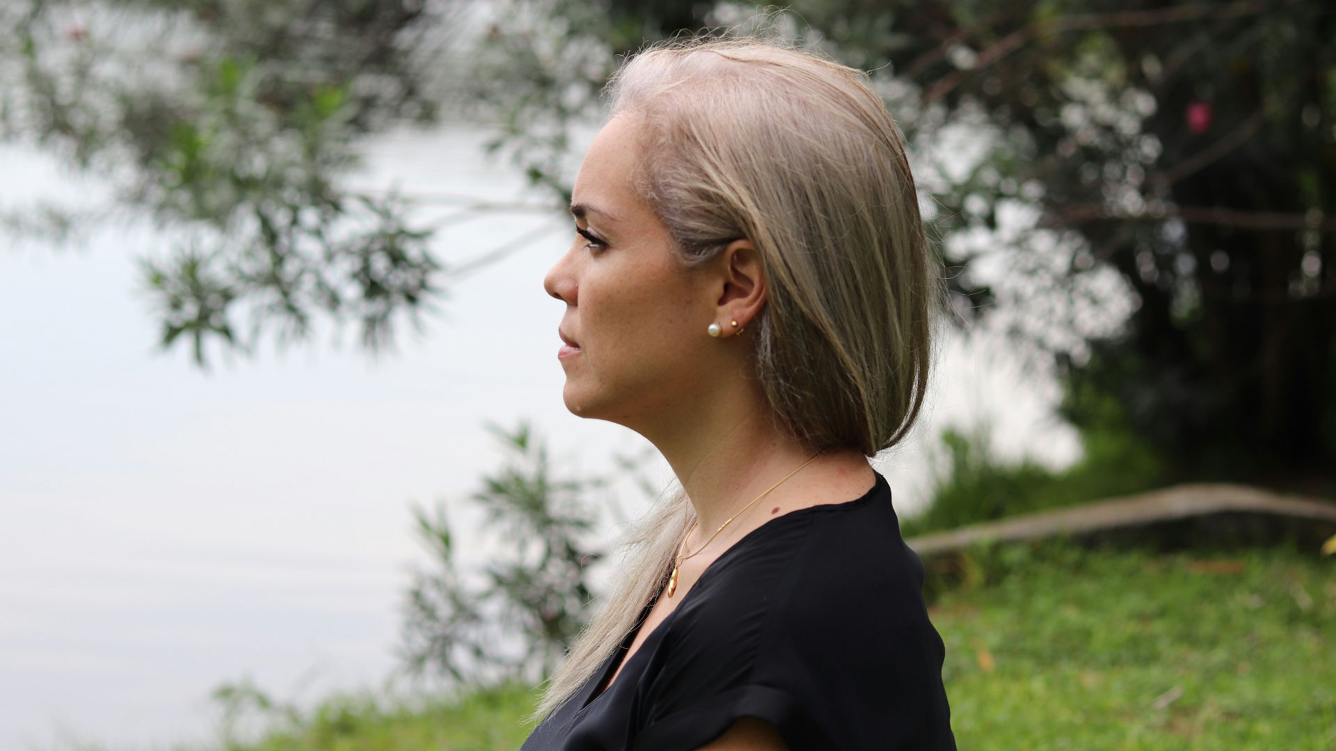 a woman with blonde hair standing in front of a body of water