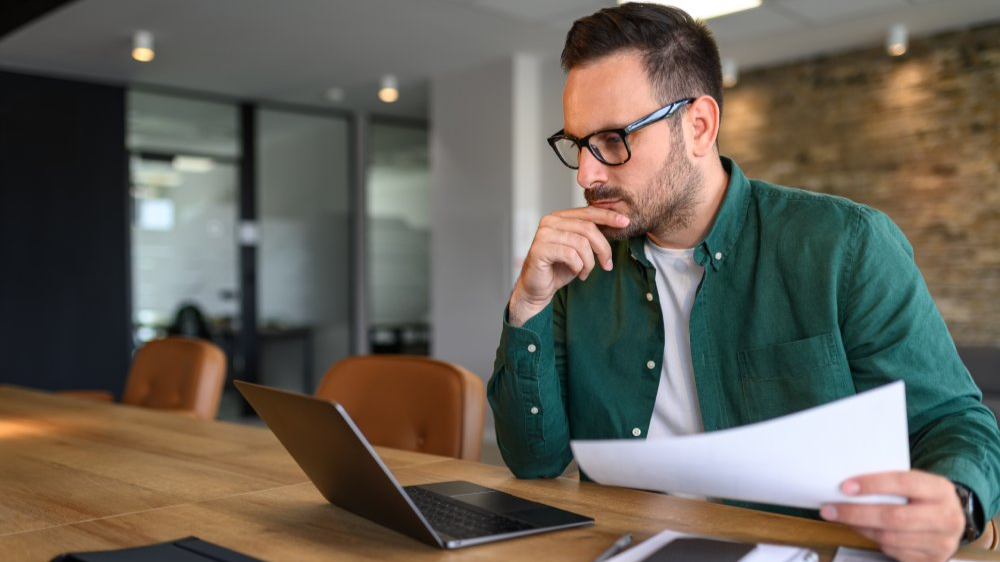 Focused young businessman auditing revenue report and planning budget