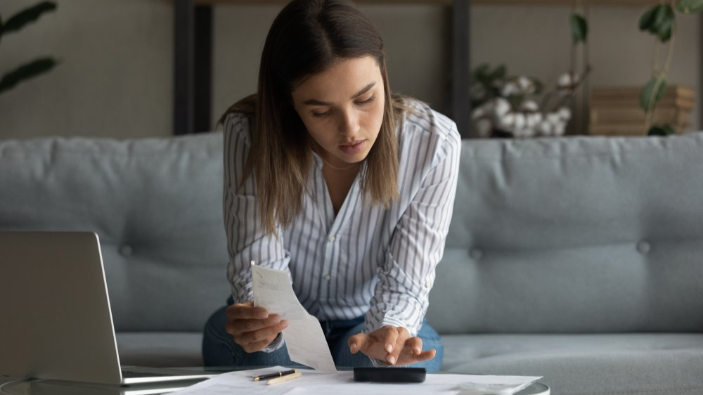 Young woman wife work with bills invoices at home