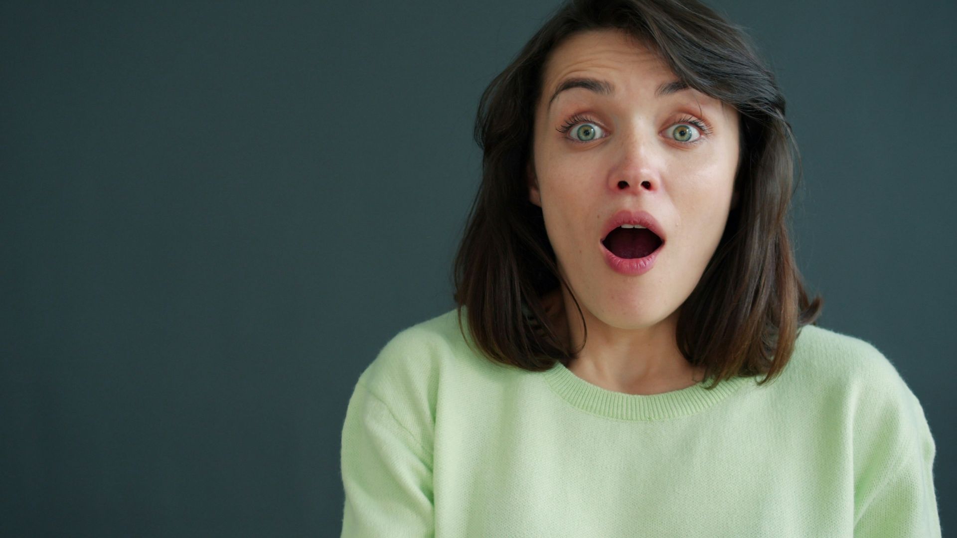 Woman with surprised expression against dark background