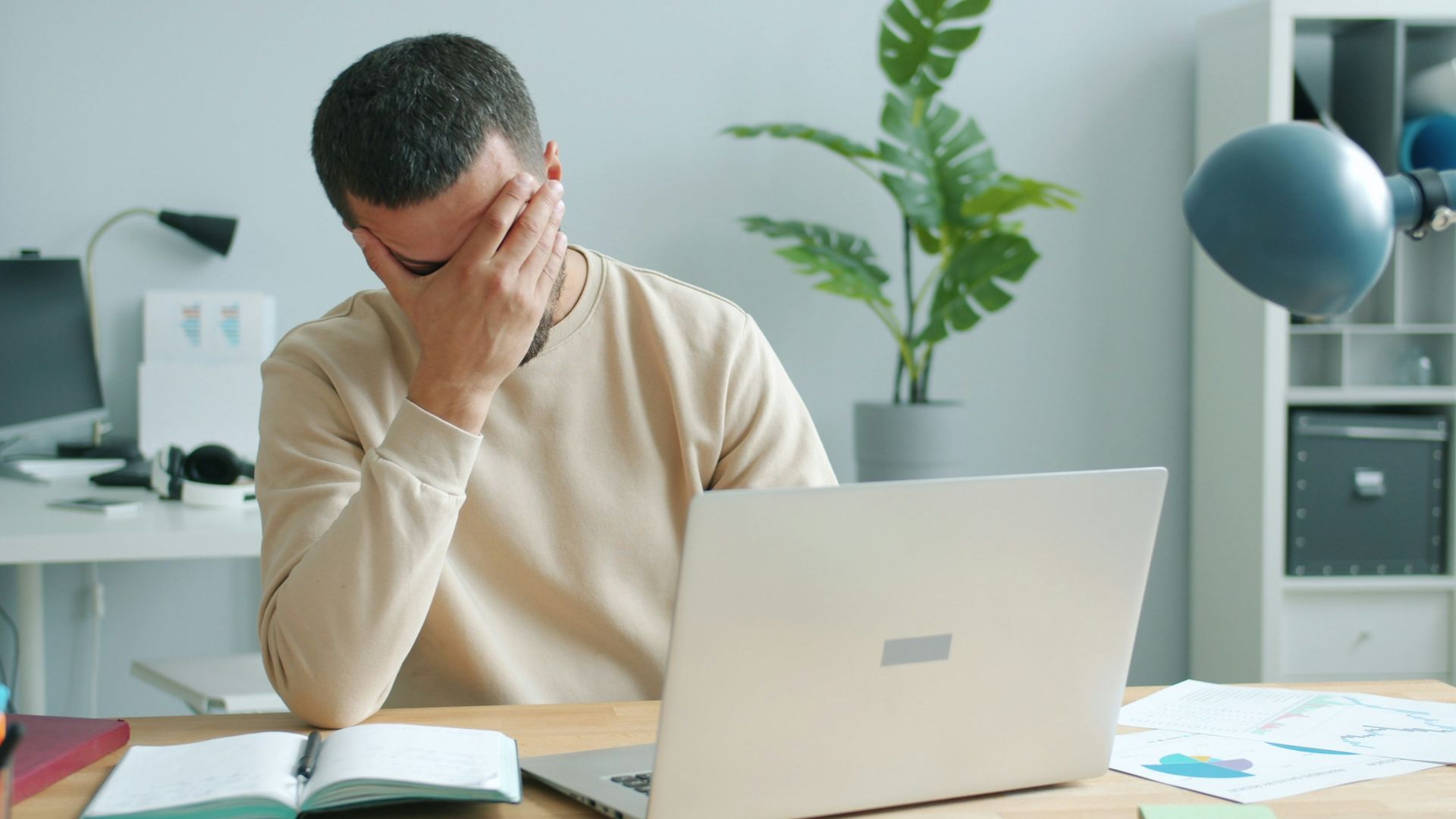 Man rubbing his face in front of laptop.