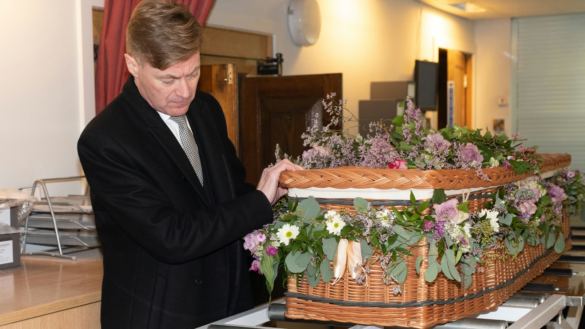 a man in a suit and tie holding a basket of flowers