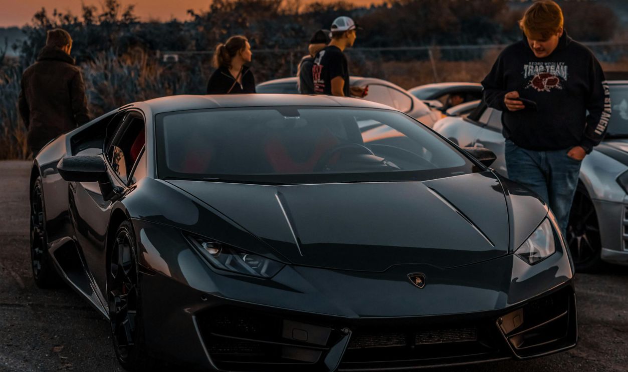 Man Standing Beside a Black Sports Car