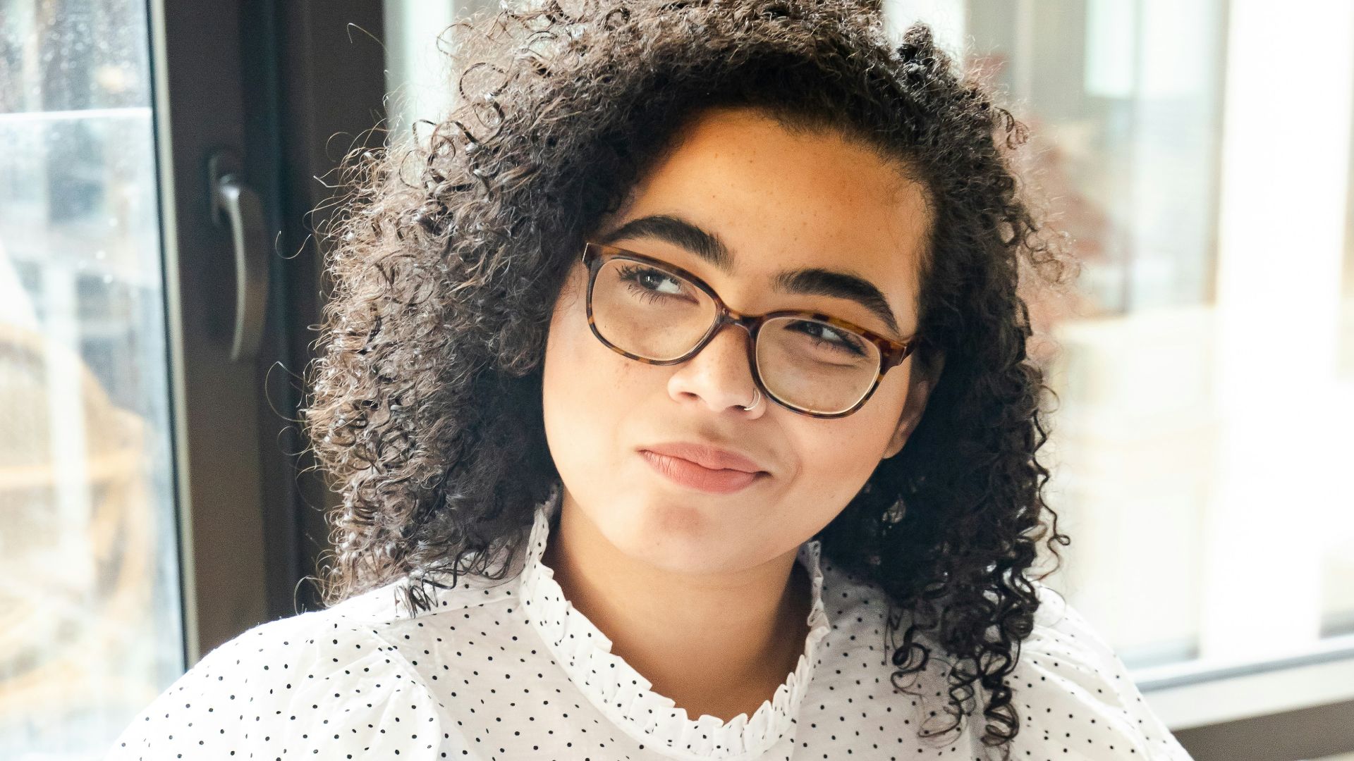 woman in white and black polka dot shirt holding blue and white book