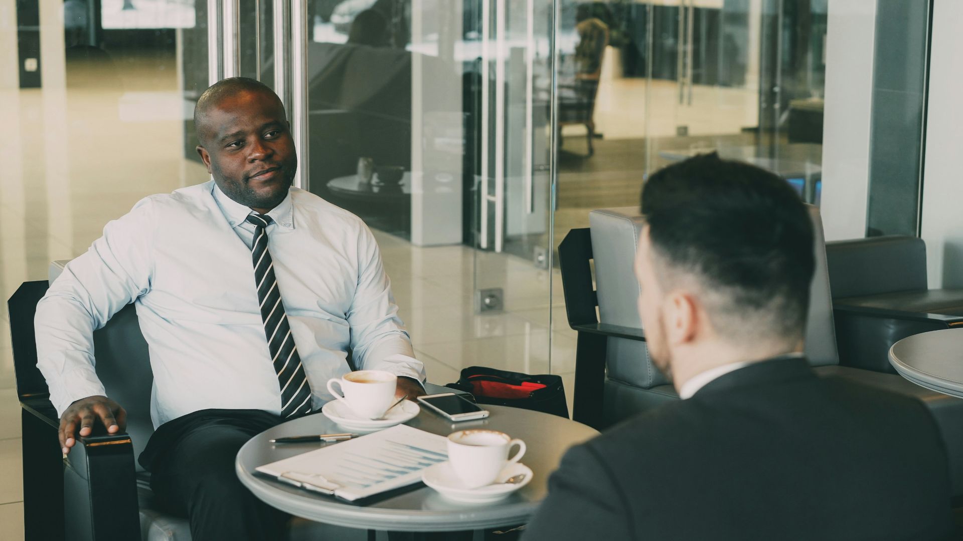 Two businessmen talking at a cafe table.