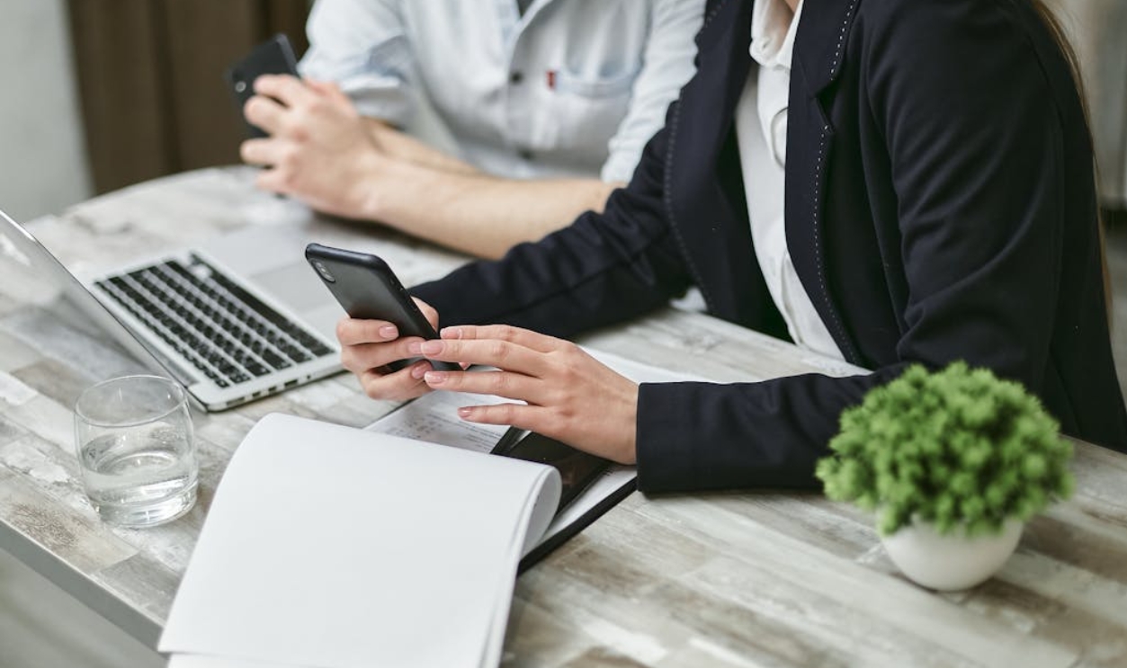 /a-woman-in-black-suit-jacket-holding-a-black-smartphone
